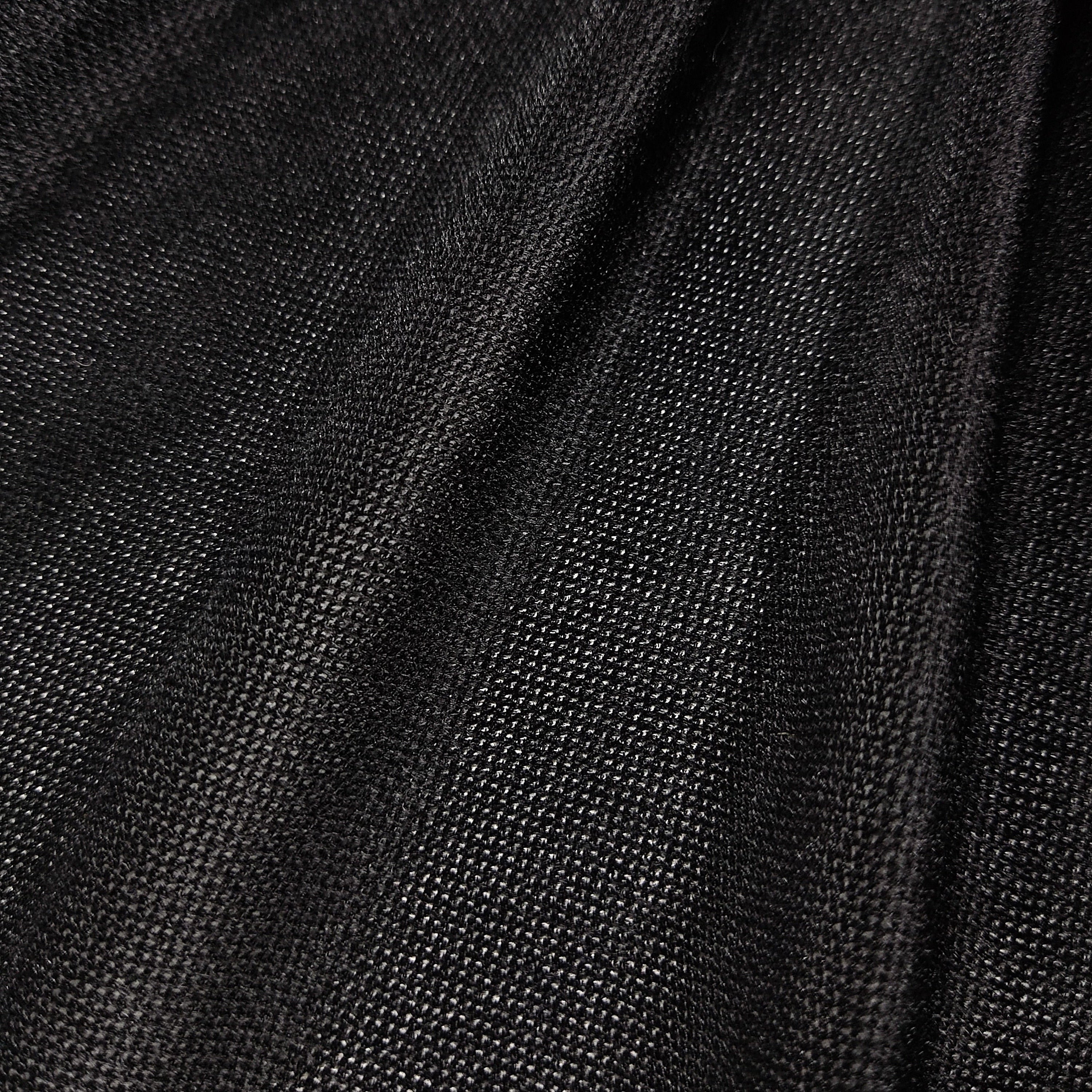A close-up of black textured fabric with a fine woven pattern and soft folds.