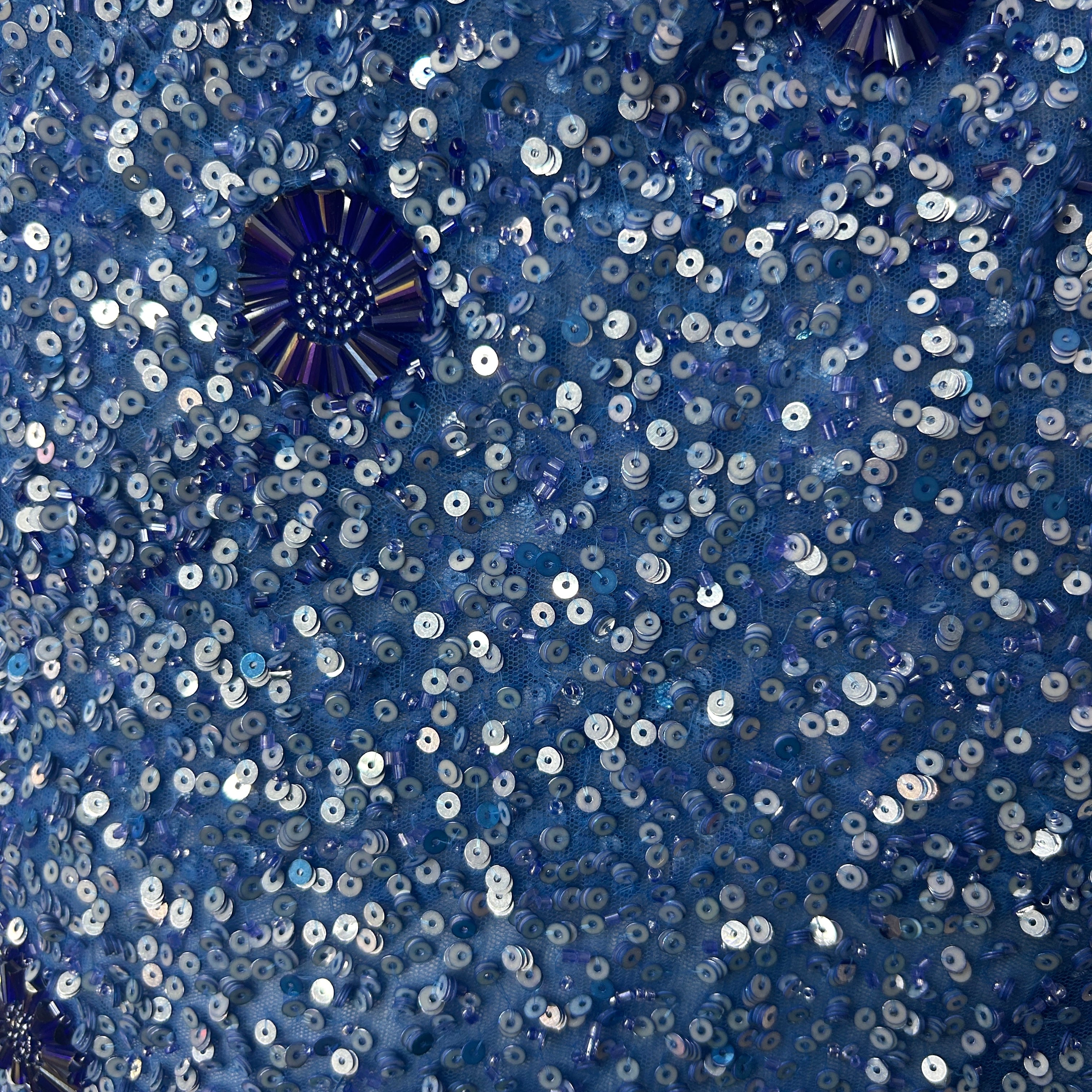 Close-up of blue sequin fabric with a star-shaped brooch.