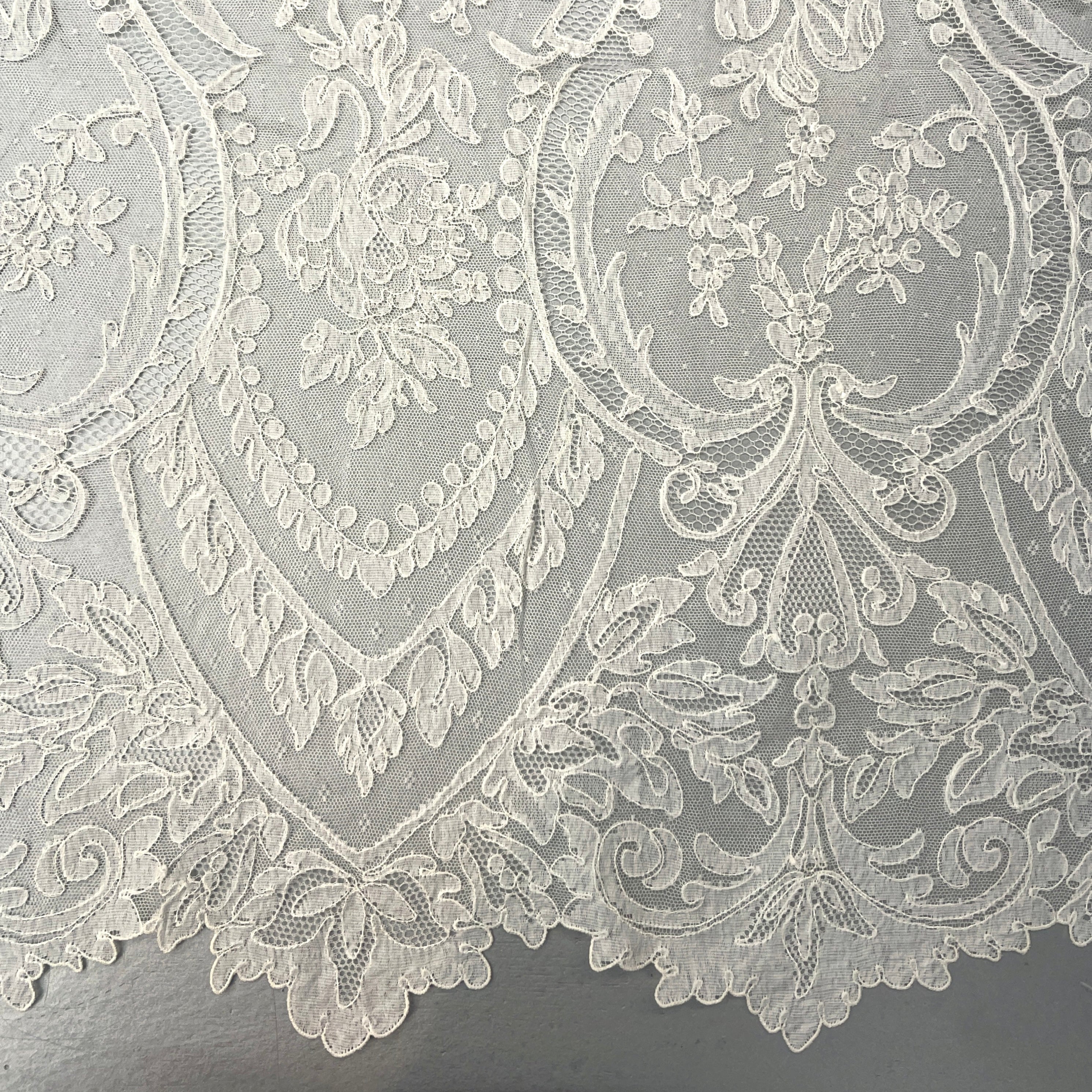 Close-up of intricate lace fabric with floral patterns on a gray background