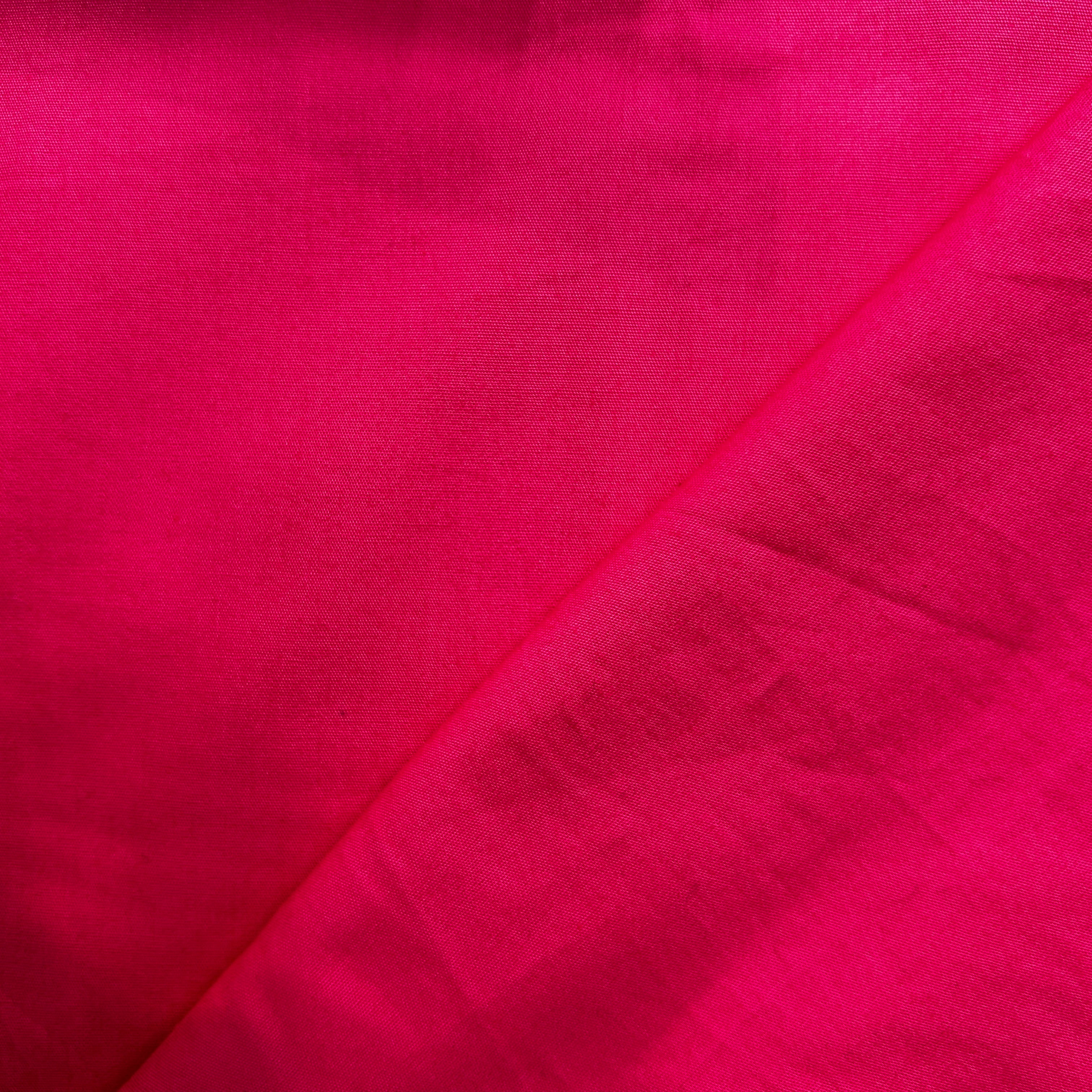 Close-up of bright pink fabric with a diagonal seam