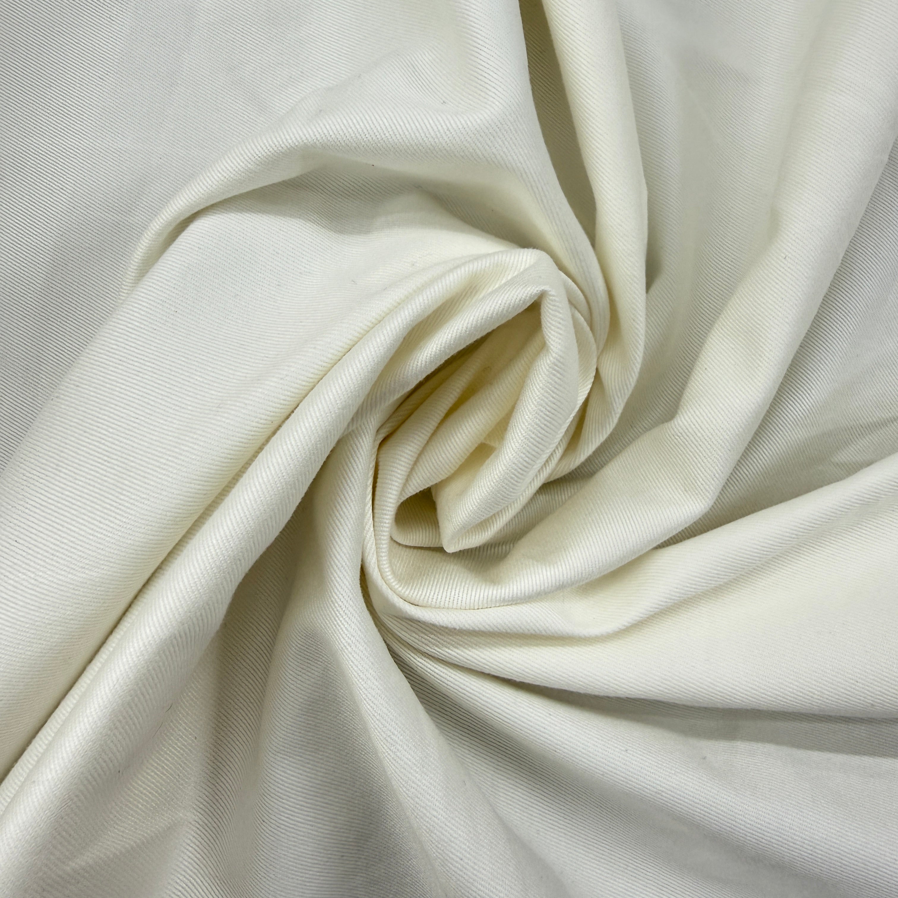 A close-up of draped off-white fabric with a subtle woven texture, arranged in a spiral pattern.