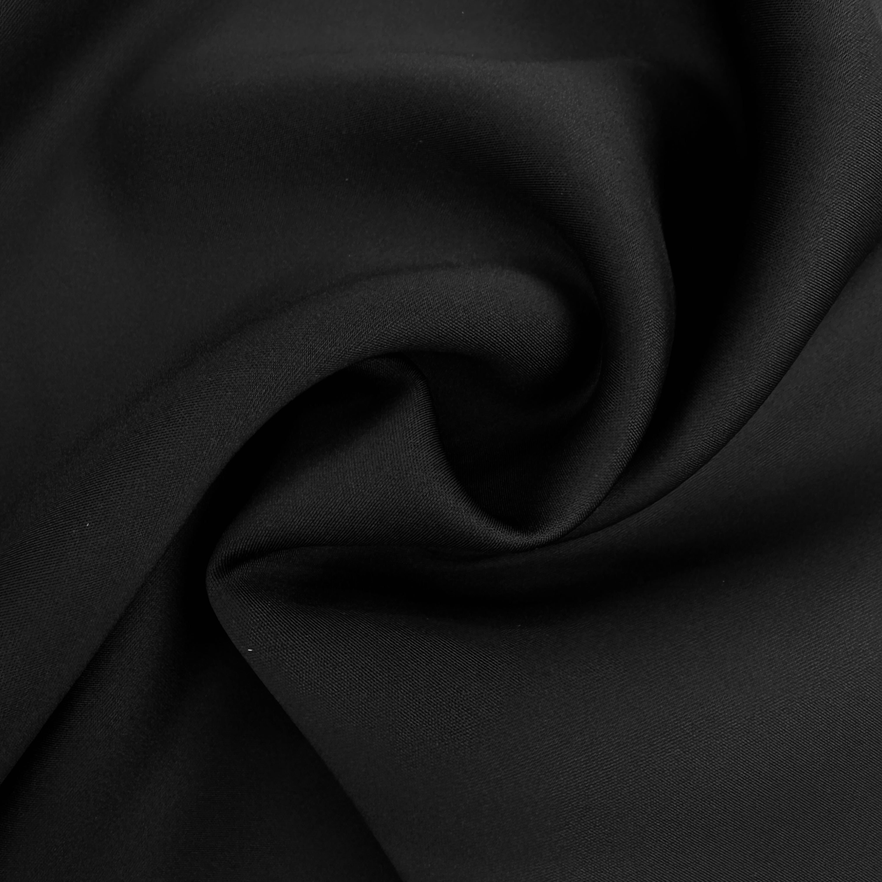 A close-up of draped black fabric with soft folds and a smooth texture.
