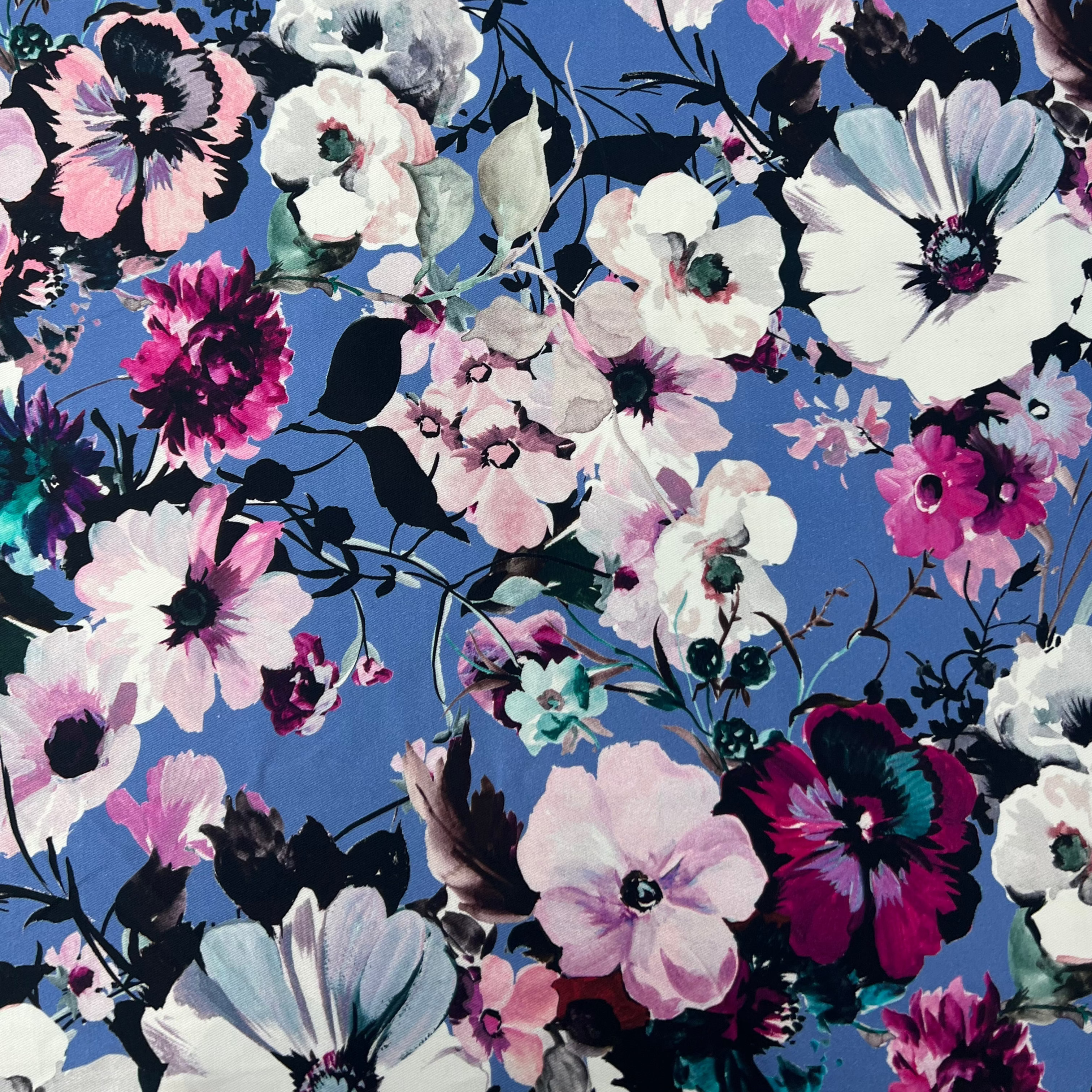 Blue cotton twill fabric featuring a vibrant floral print with white, pink, and purple flowers.