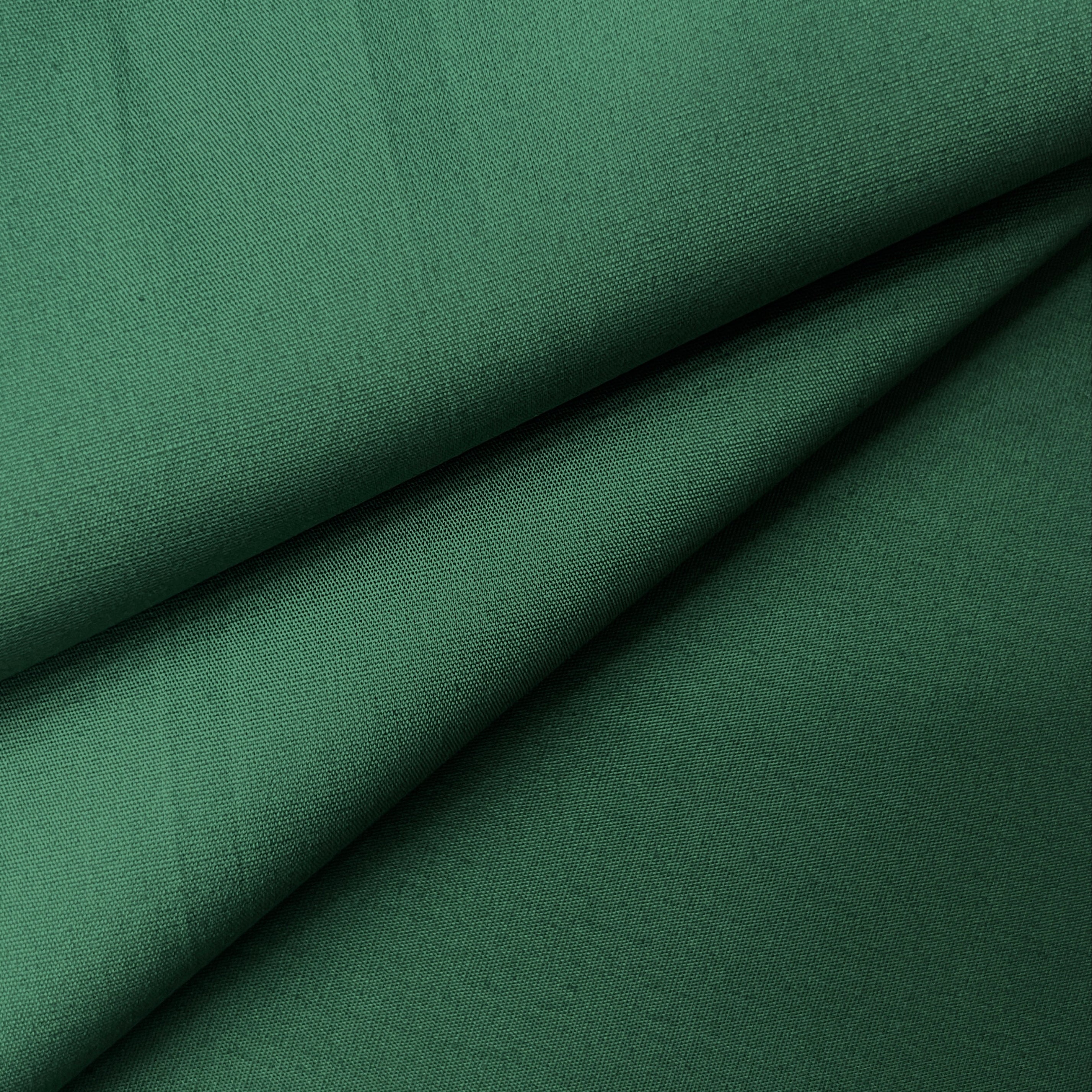Close-up of green 100% cotton poplin plain weave fabric with soft folds.