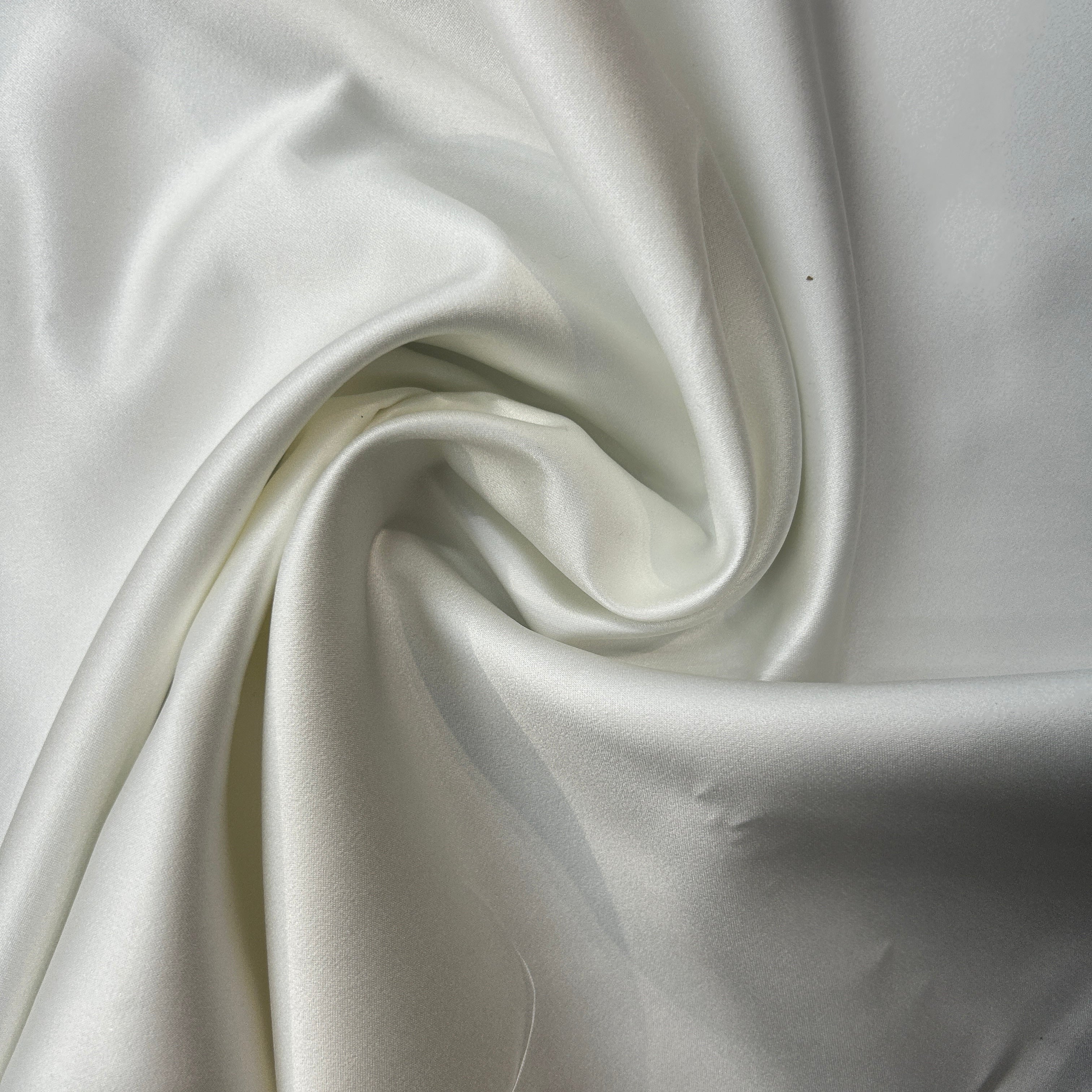 Close-up of white satin fabric with folds