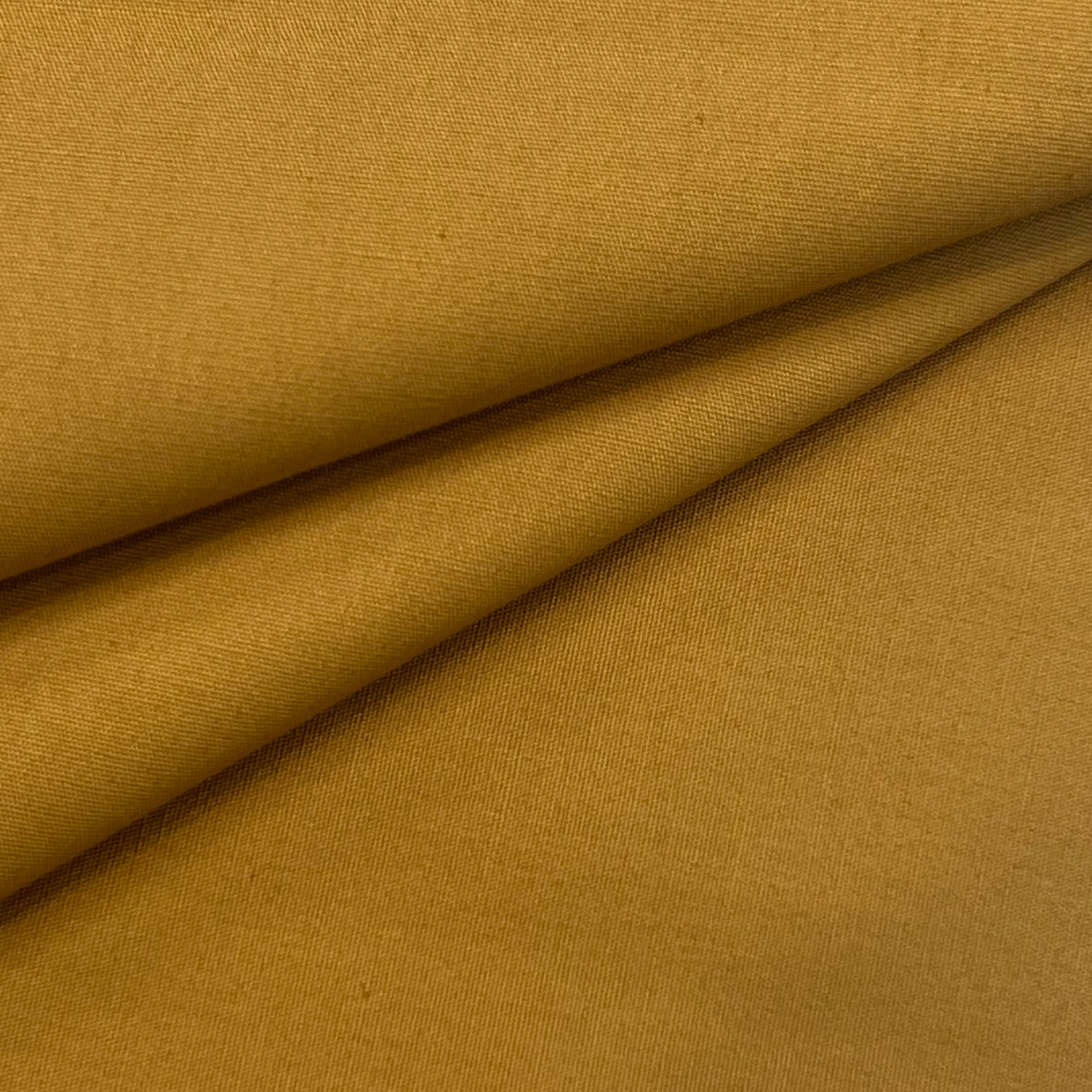 A folded swatch of golden brown cotton poplin fabric.