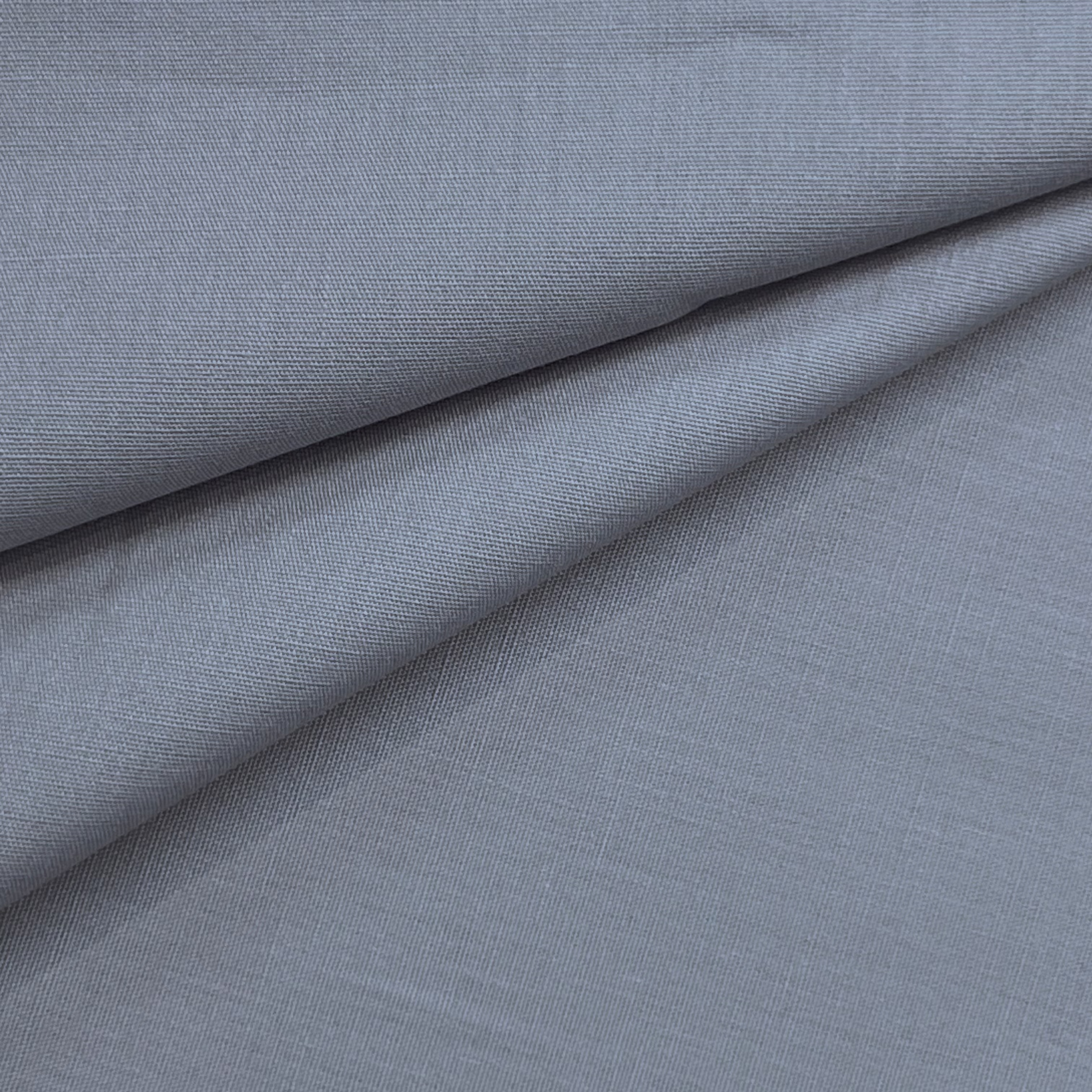 A close-up of smooth, light blue cotton poplin fabric with a fine, crisp weave and soft folds.