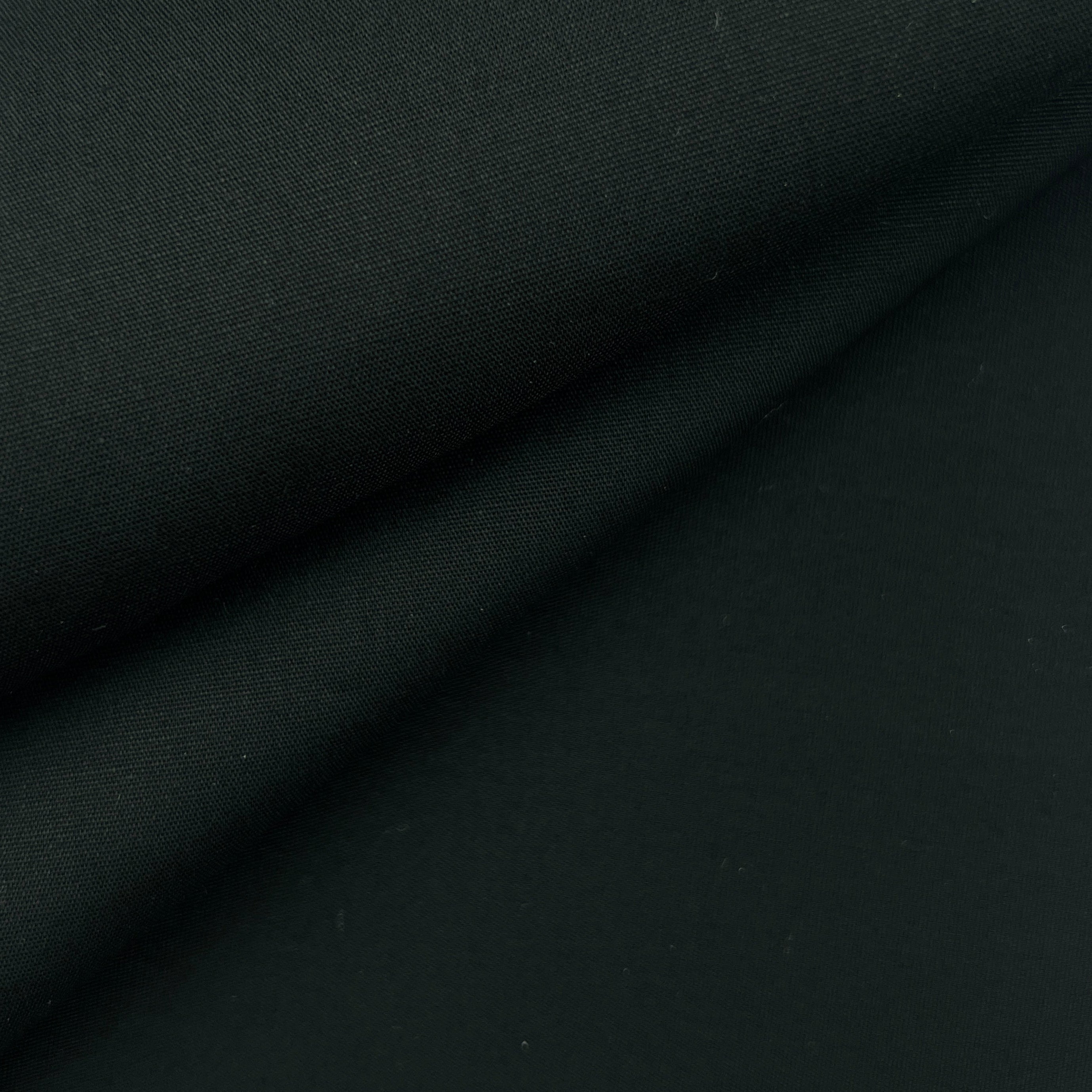 A close-up of draped black fabric with soft folds and a smooth matte texture.