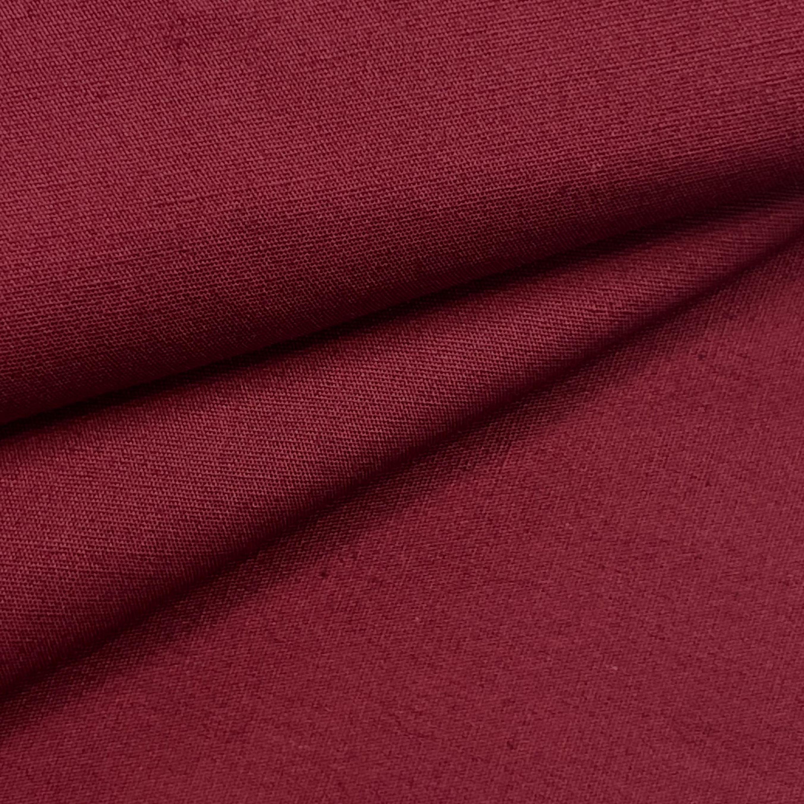 Close-up of a deep burgundy cotton poplin fabric with a fine, smooth weave and soft folds.