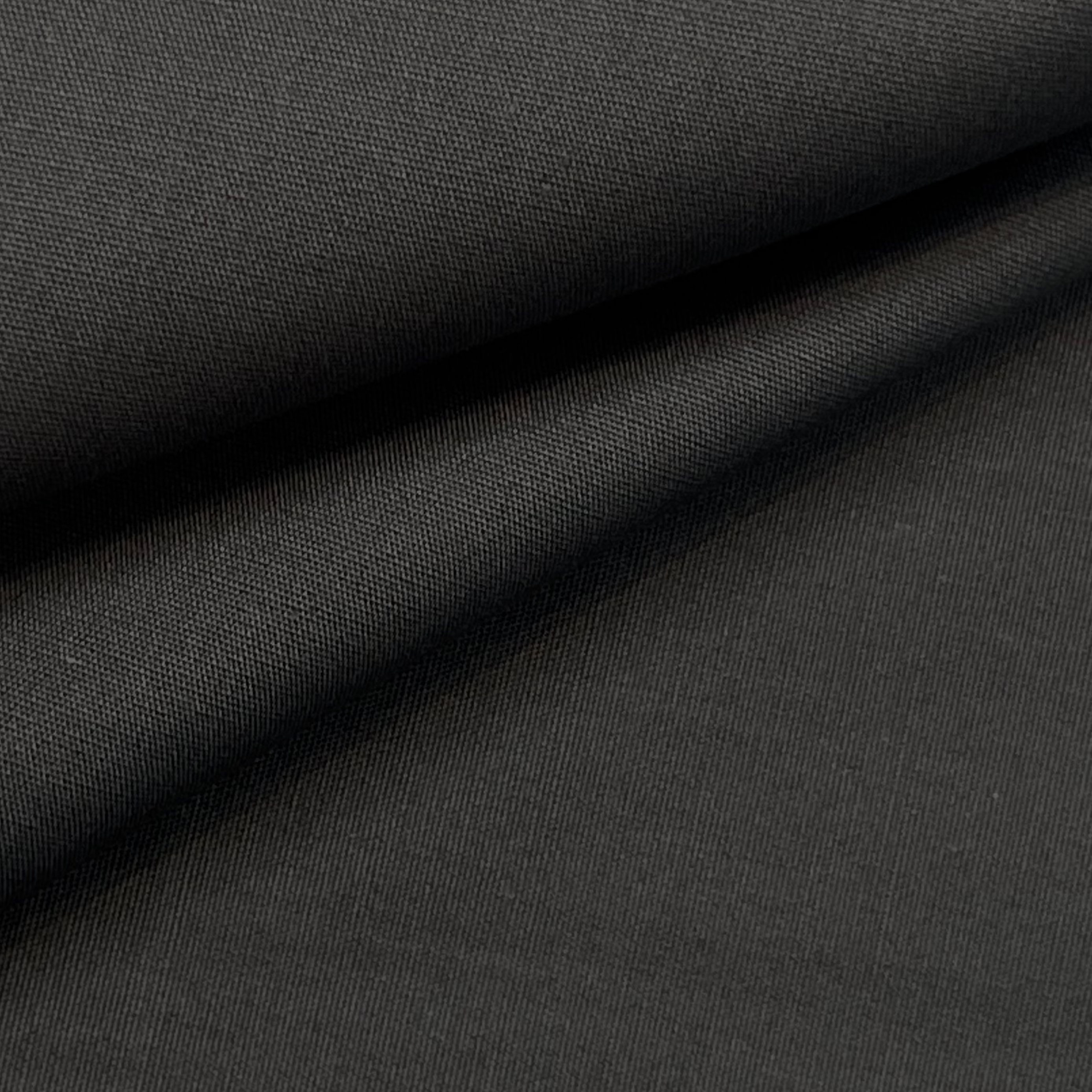 Close-up of black cotton poplin fabric showing its fine, smooth weave and soft folds.