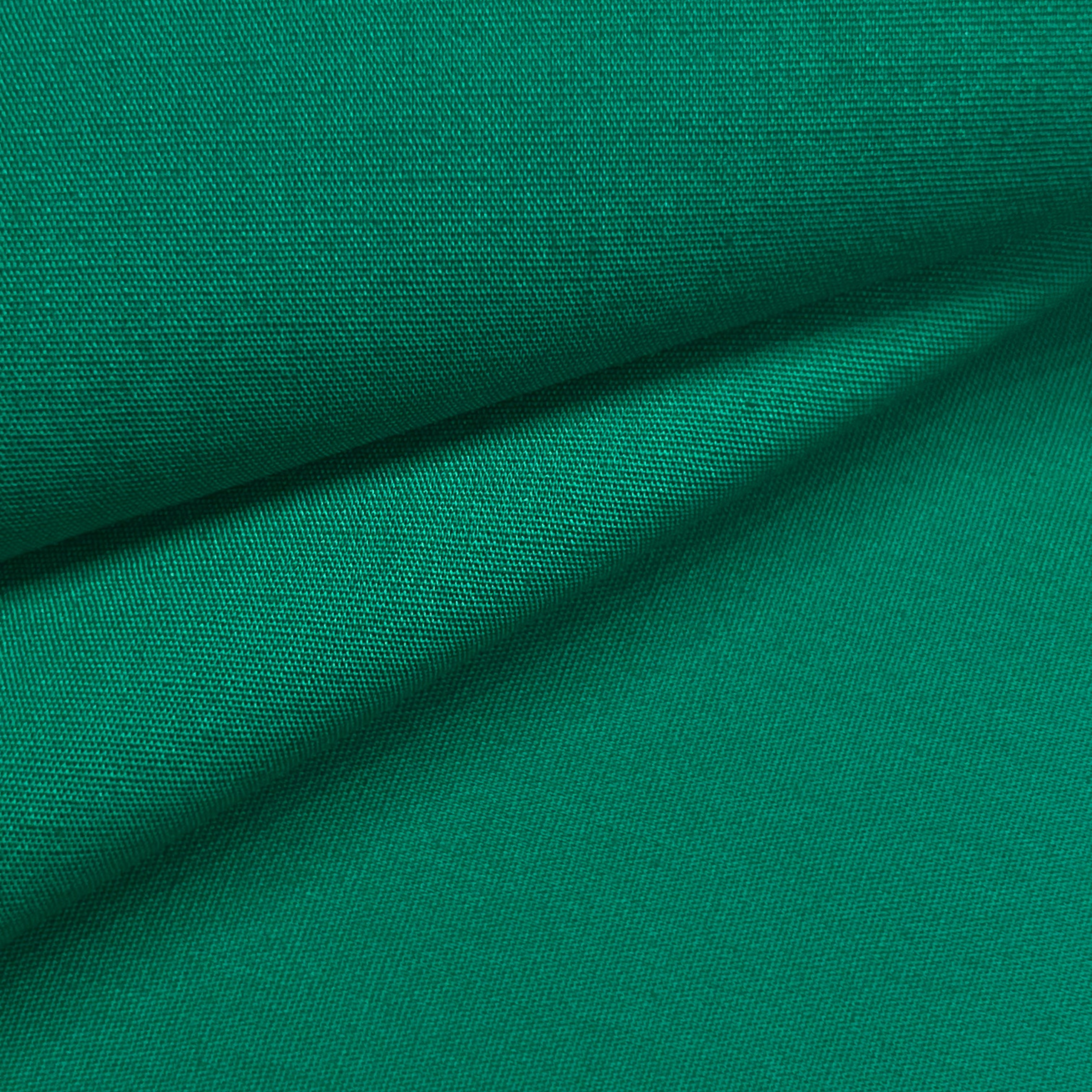 A close-up of emerald green cotton poplin fabric showing its fine plain weave and smooth texture.