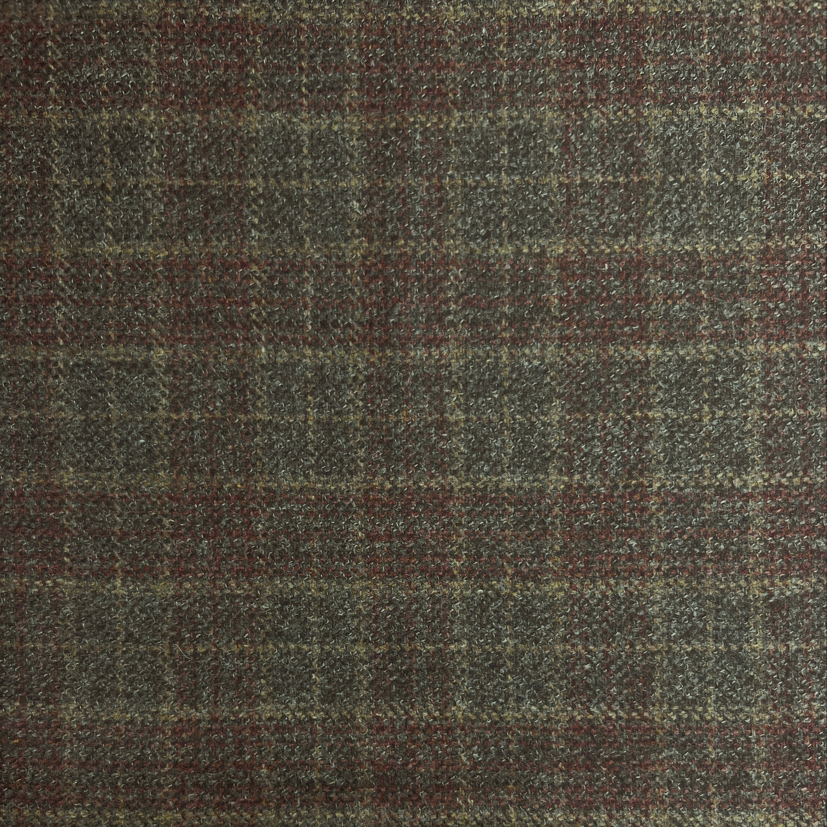 A close-up of a textured tweed fabric with a classic windowpane plaid pattern in dark gray, brown, and muted red.