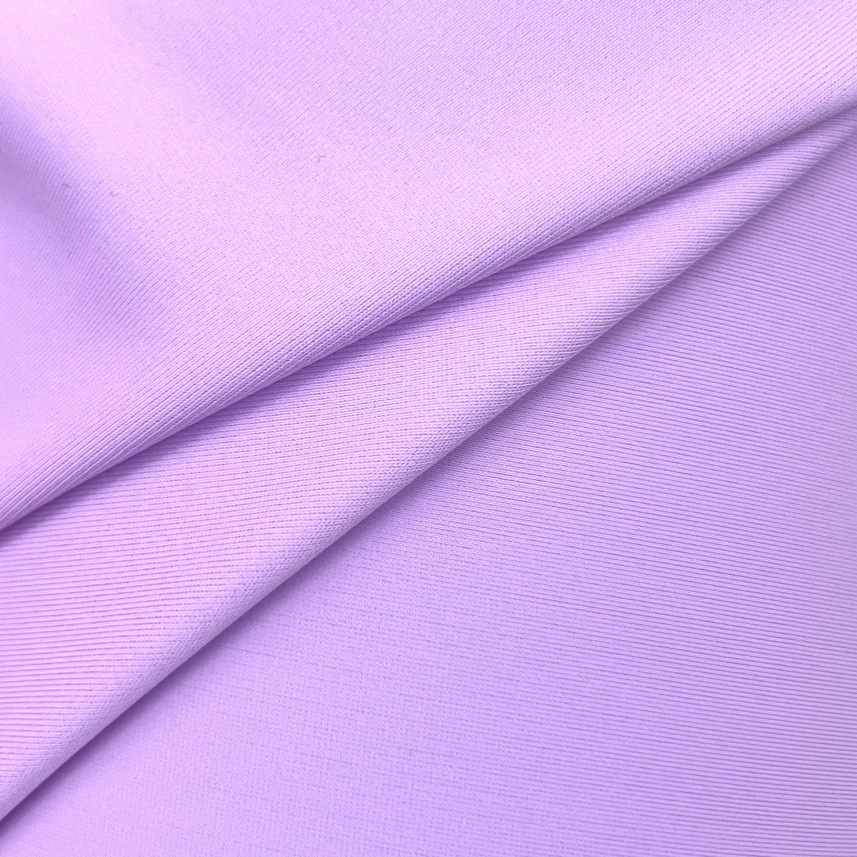 A close-up of lavender purple fabric with a fine ribbed texture, folded diagonally across the frame.