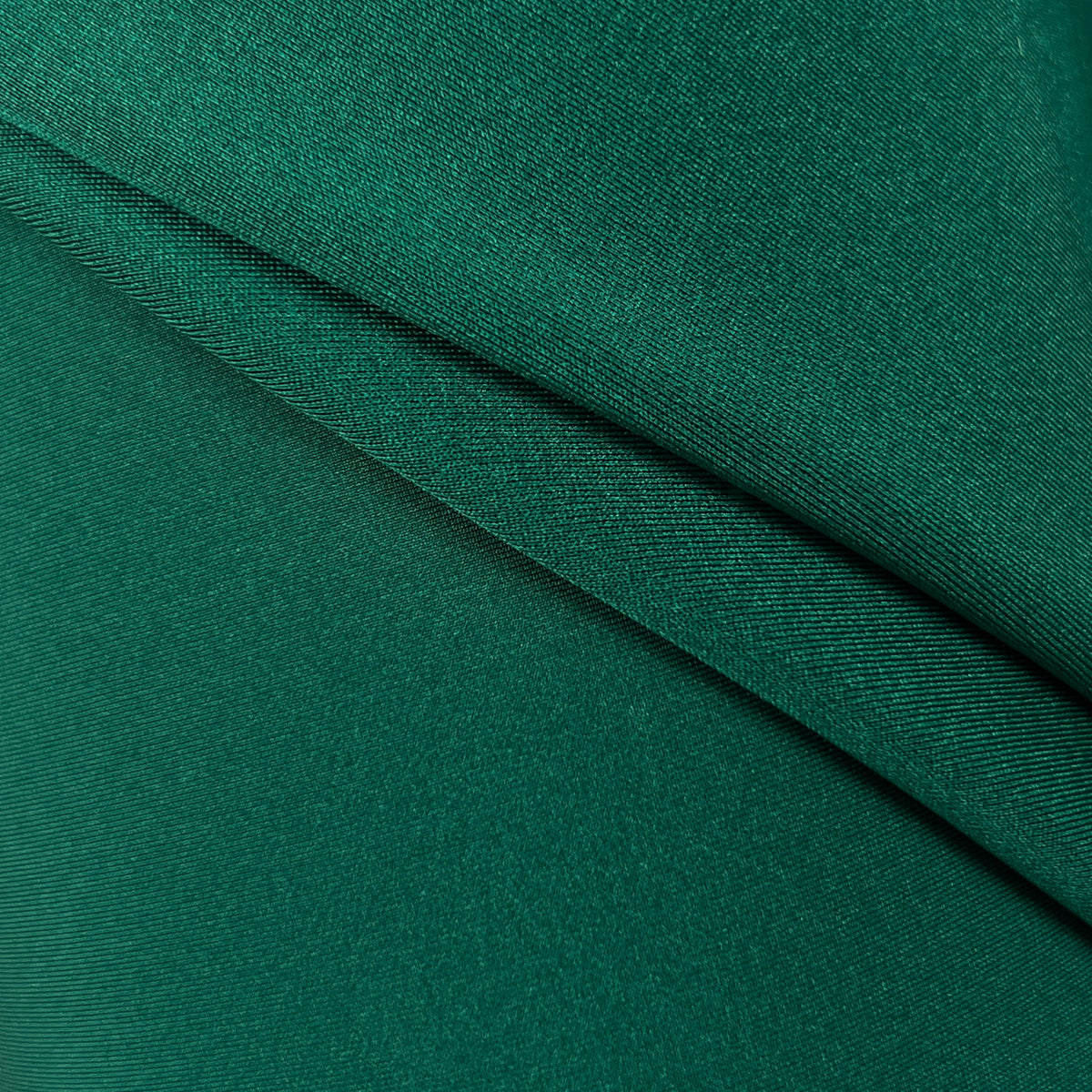 A close-up of draped emerald green fabric with a fine textured weave.
