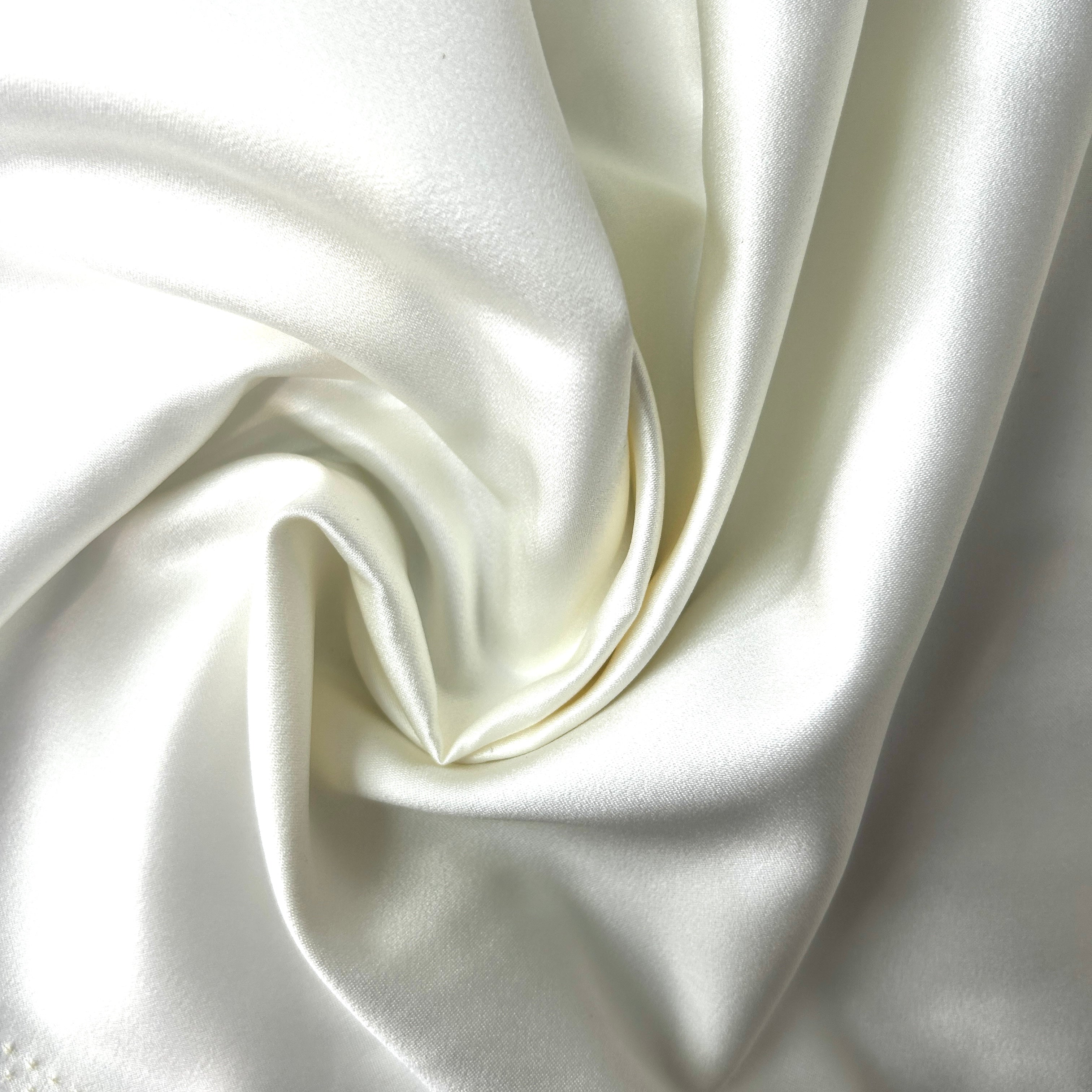 Close-up of white satin fabric with folds