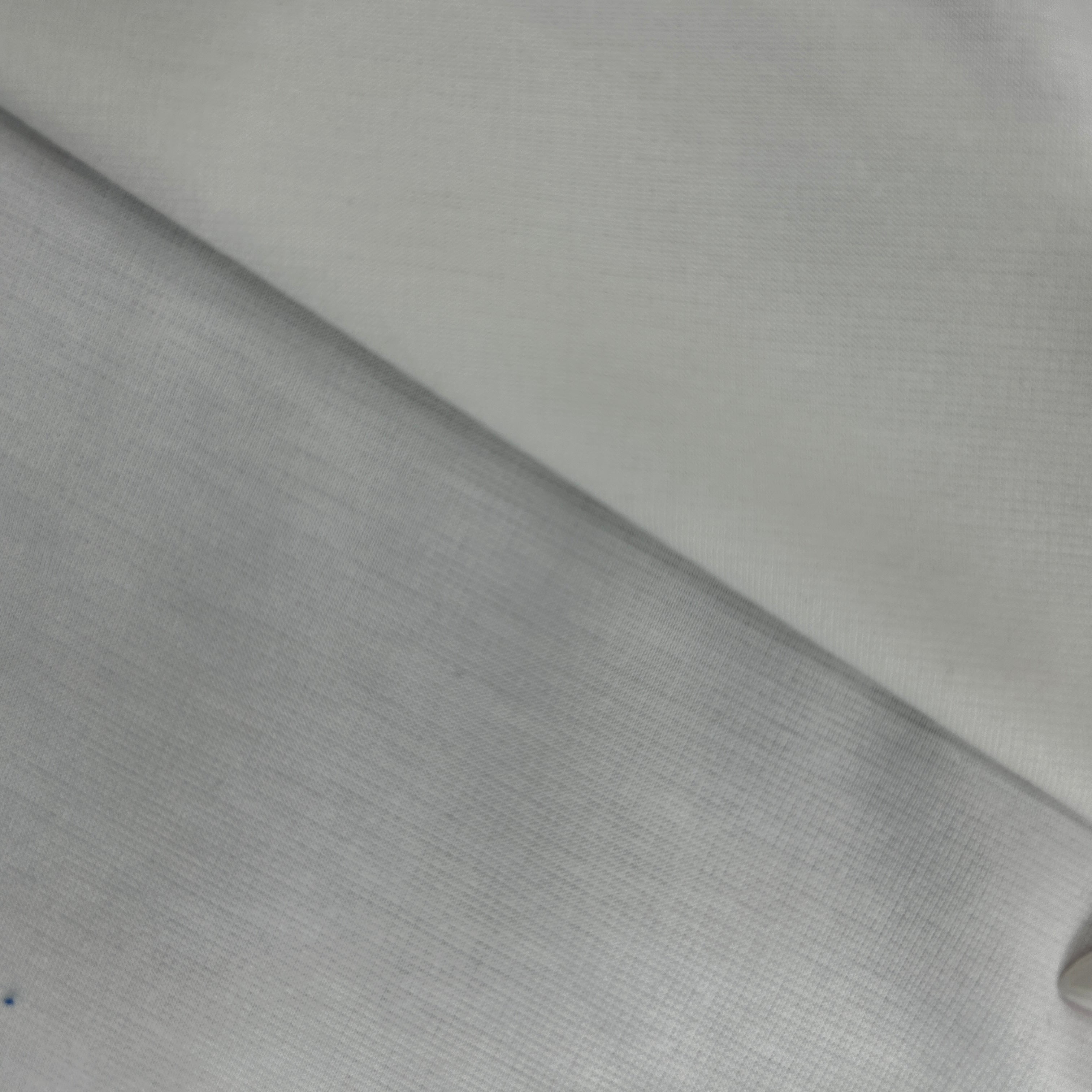 A close-up of light gray fabric with a fine woven texture, folded diagonally across the frame.