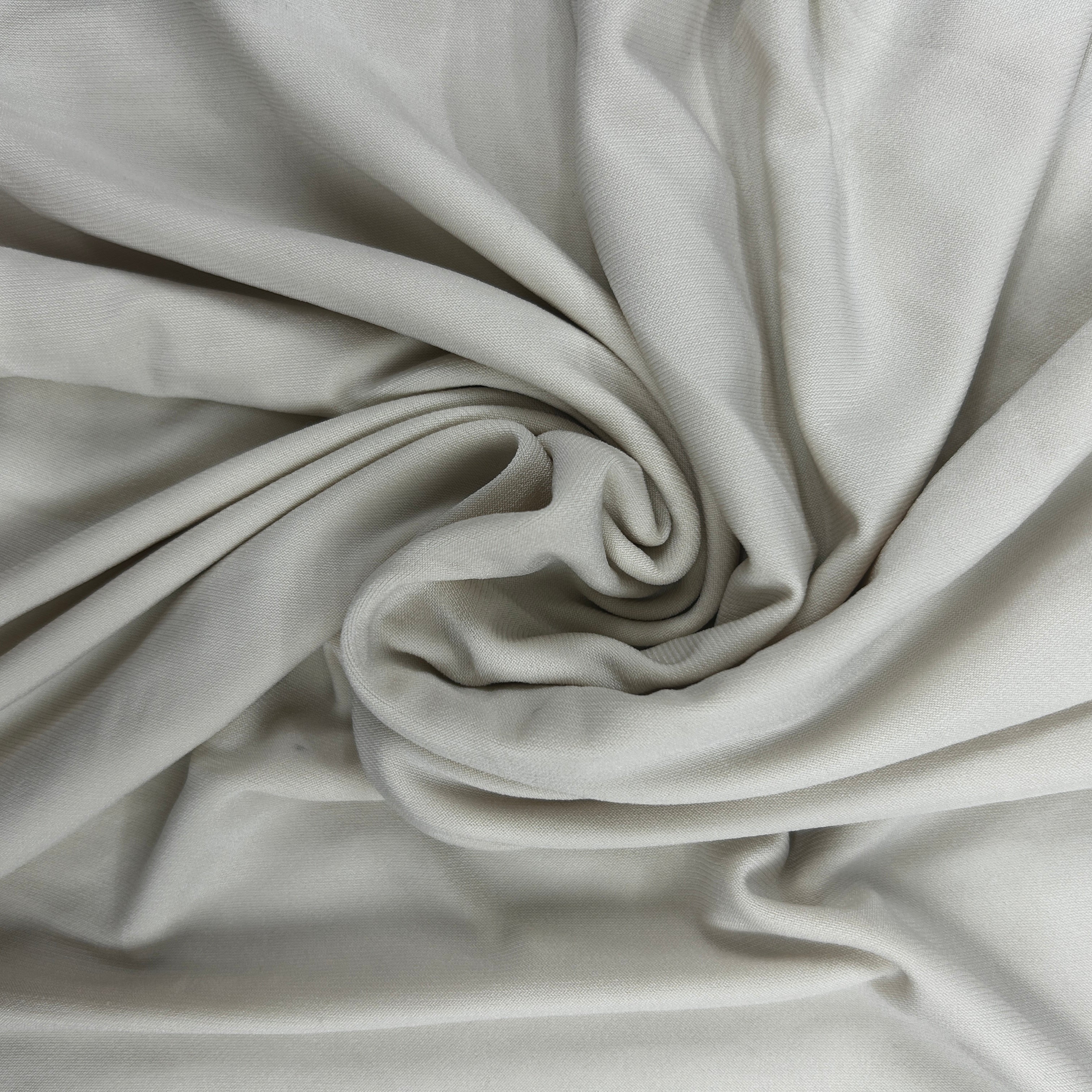 A close-up of draped light gray fabric arranged in a spiral, showing the material's soft texture and folds.