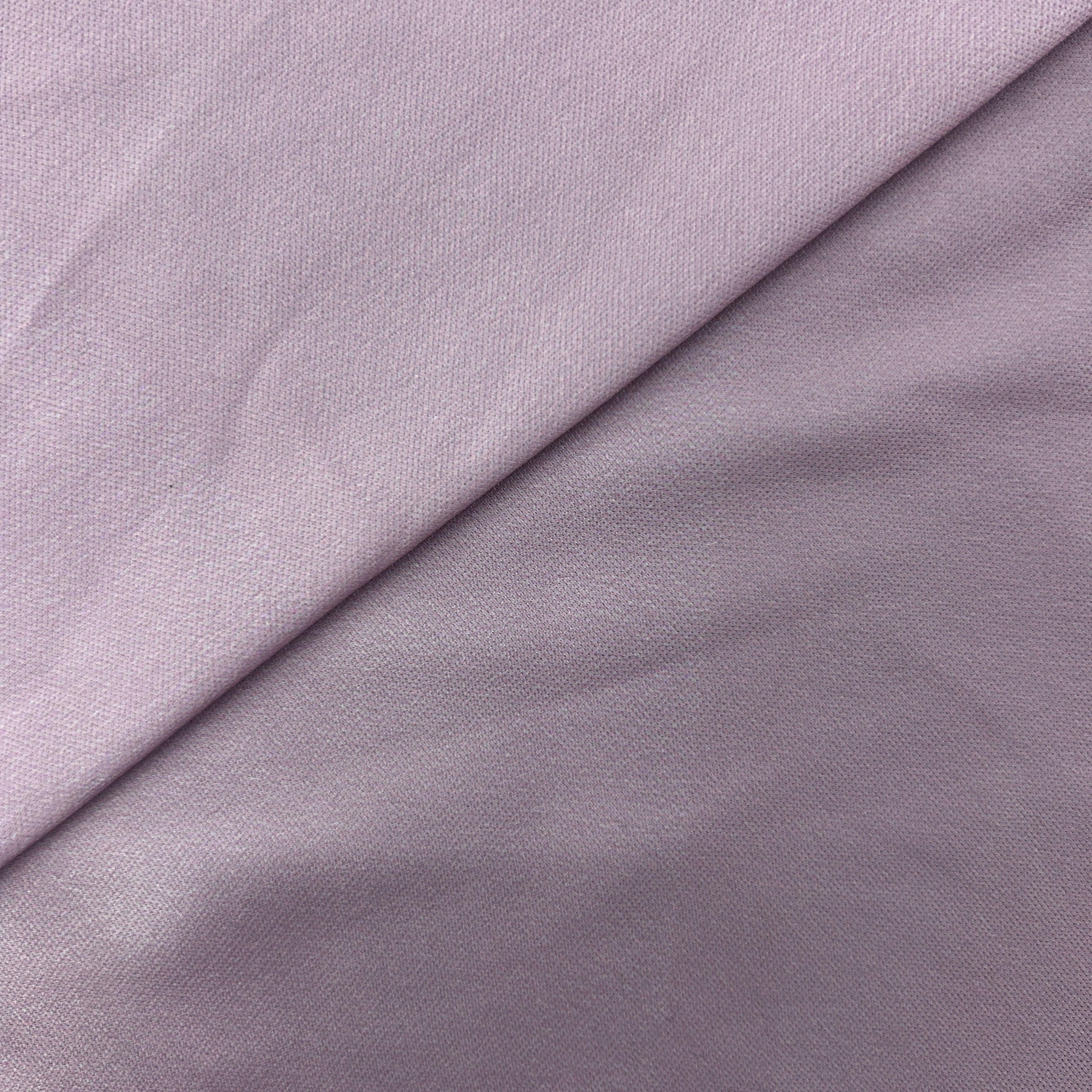 A close-up of a light lavender-gray fabric with a diagonal fold showing its fine woven texture.