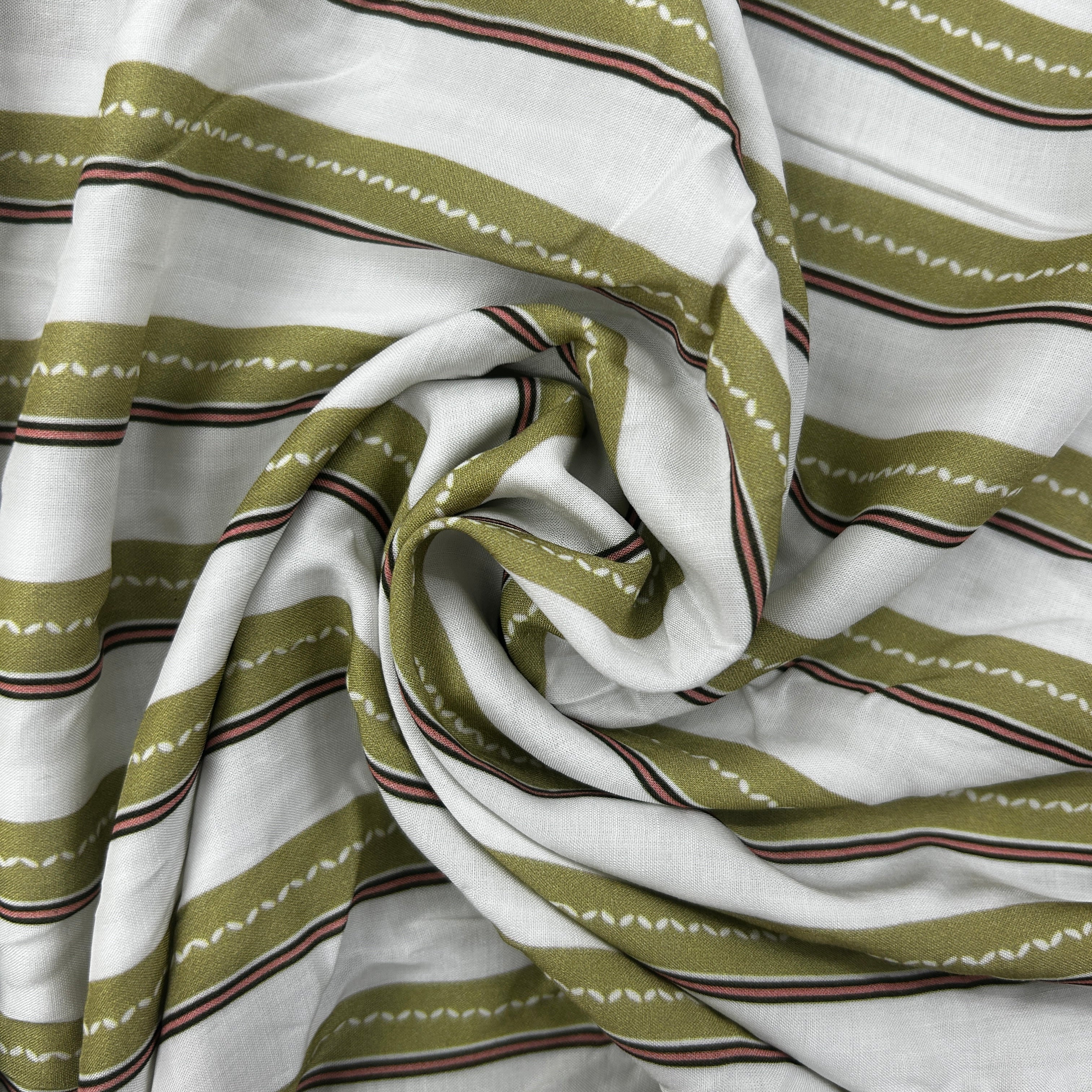 A close-up of draped fabric with a white base and horizontal olive green stripes accented by thin brown and white zigzag lines.