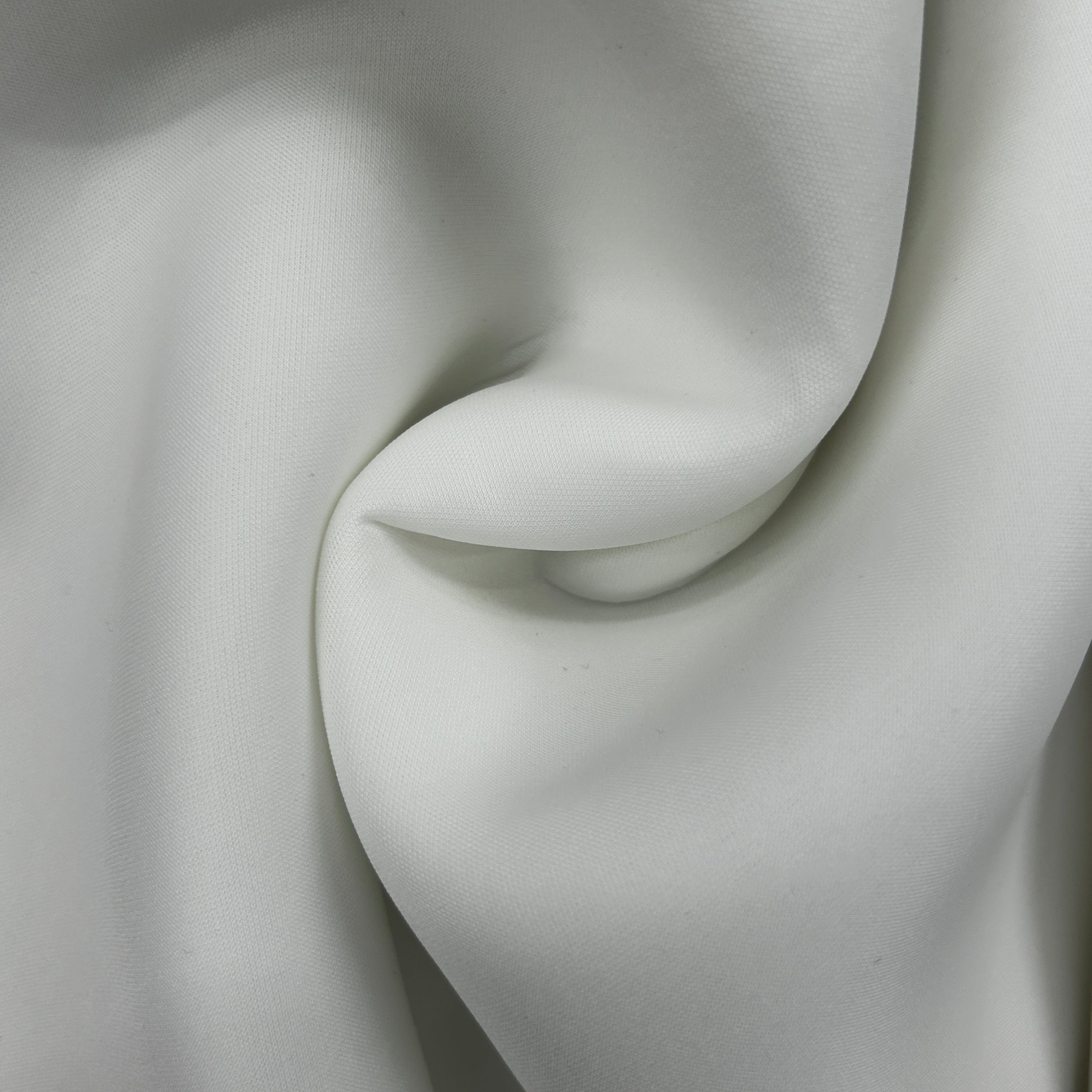 A close-up of draped white fabric with soft folds and a smooth matte texture.