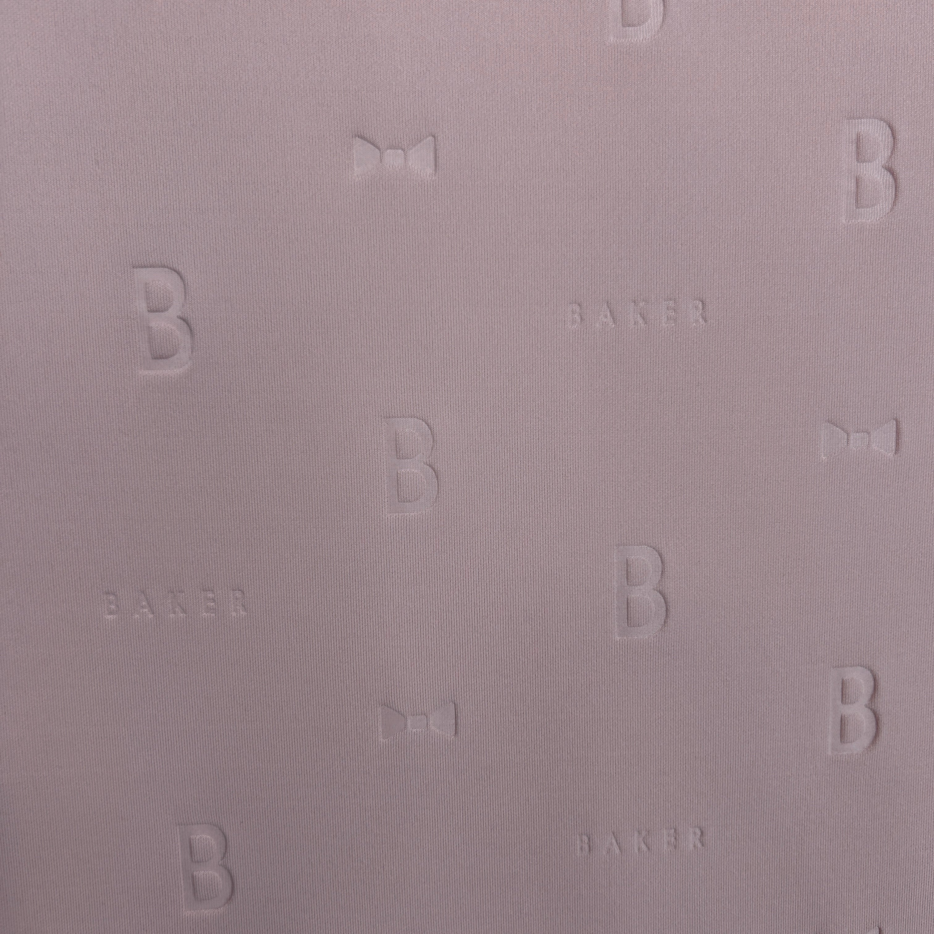 Close-up of mauve 3D Ted Baker thick scuba jersey fabric with embossed 'B', 'BAKER', and bow motifs.
