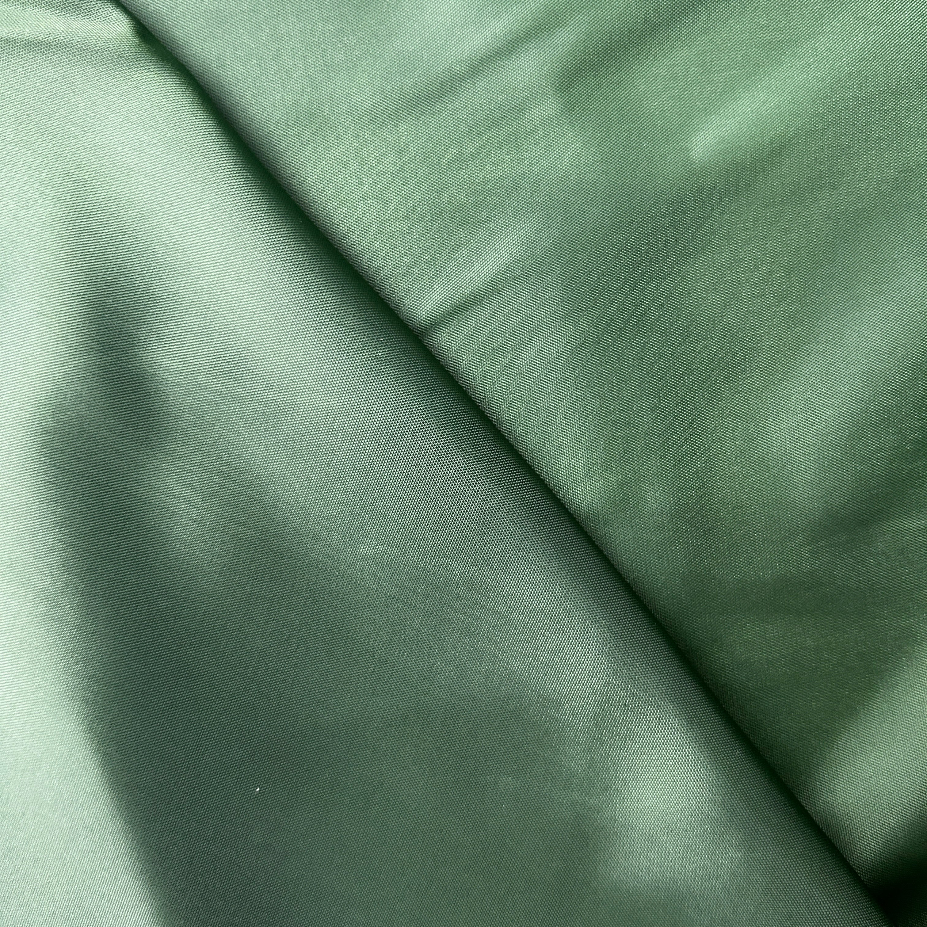 A close-up of draped sage green fabric with a subtle sheen and fine texture.