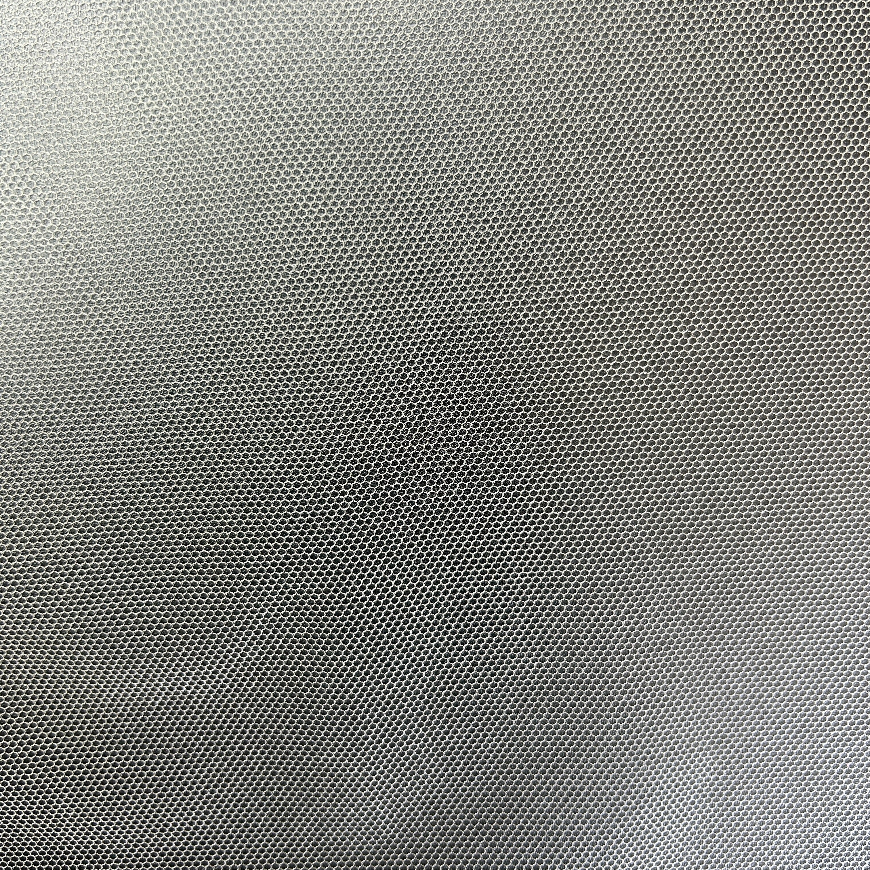Close-up of black lightweight polyester tulle mesh fabric with a fine hexagonal grid pattern.
