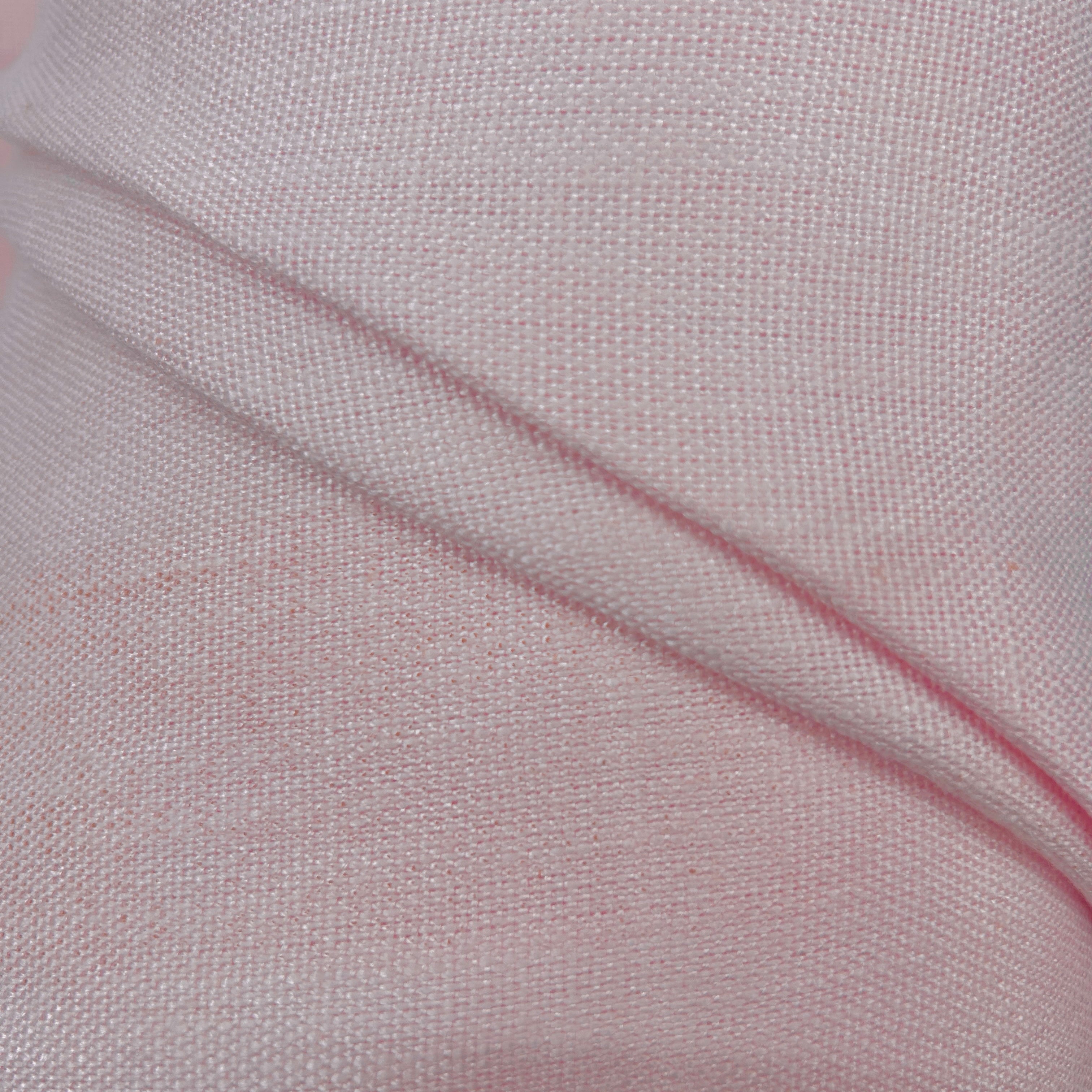 A close-up of light pink woven fabric with a visible diagonal fold showing the texture and weave.