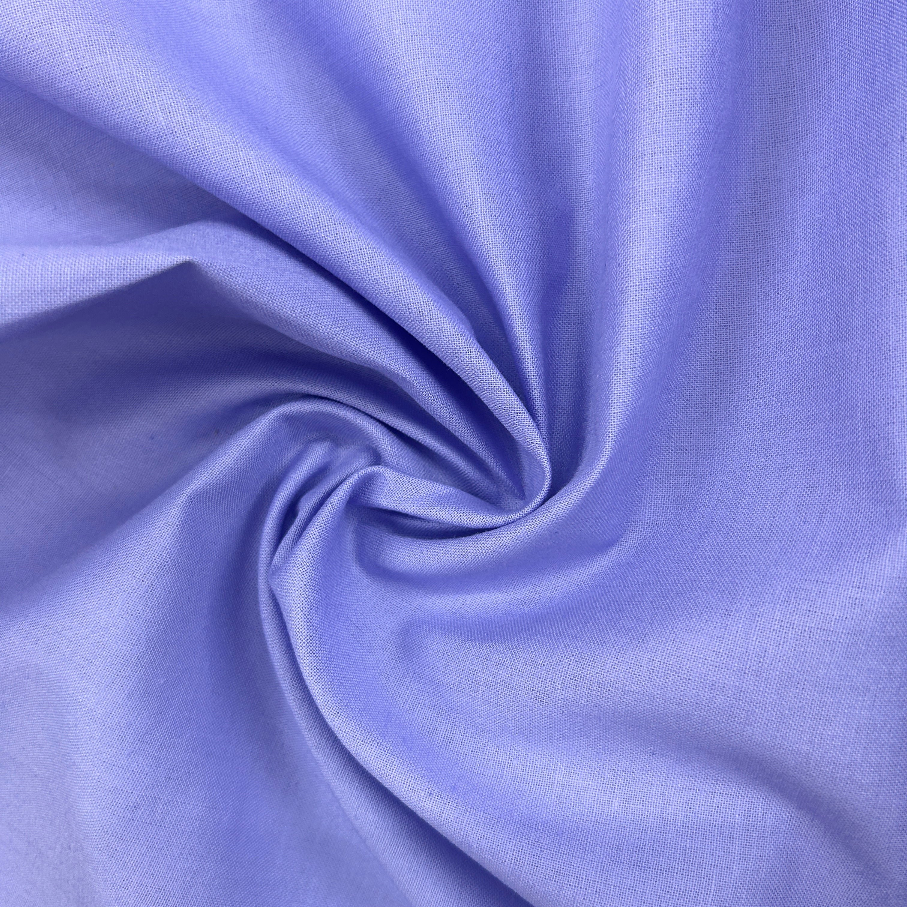 A close-up of lavender blue fabric arranged in a spiral drape, showing the material texture and color.