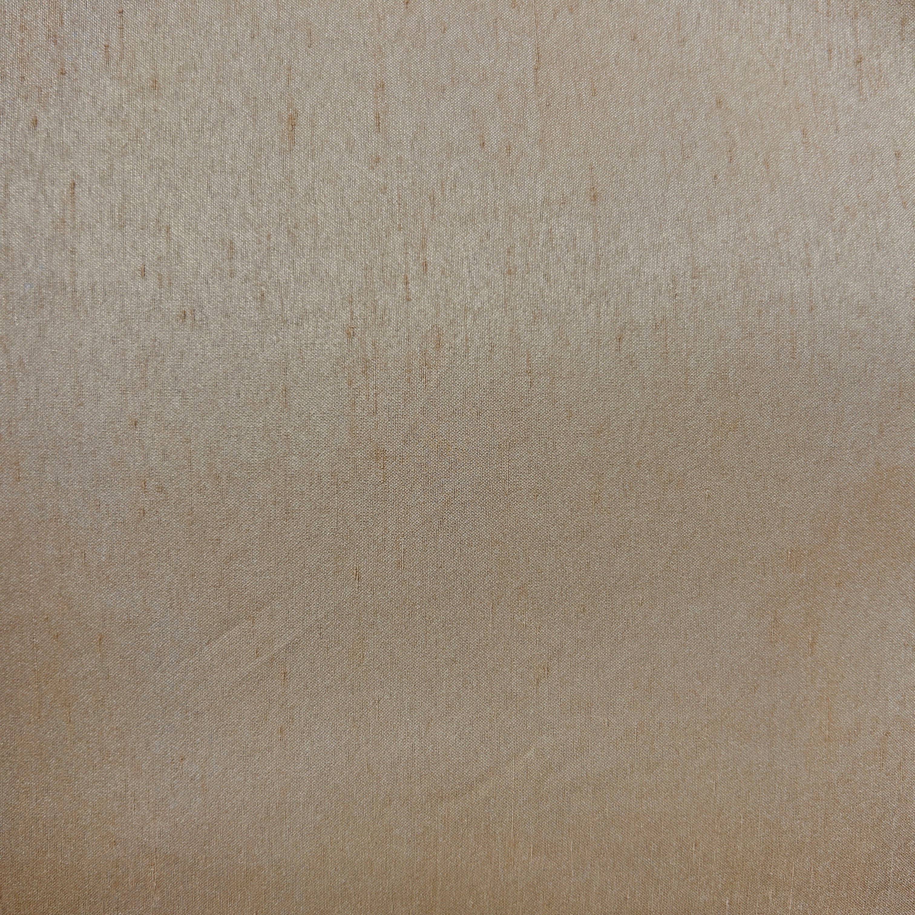 A close-up of a textured beige surface with a fine, slightly mottled grain or fabric-like pattern.