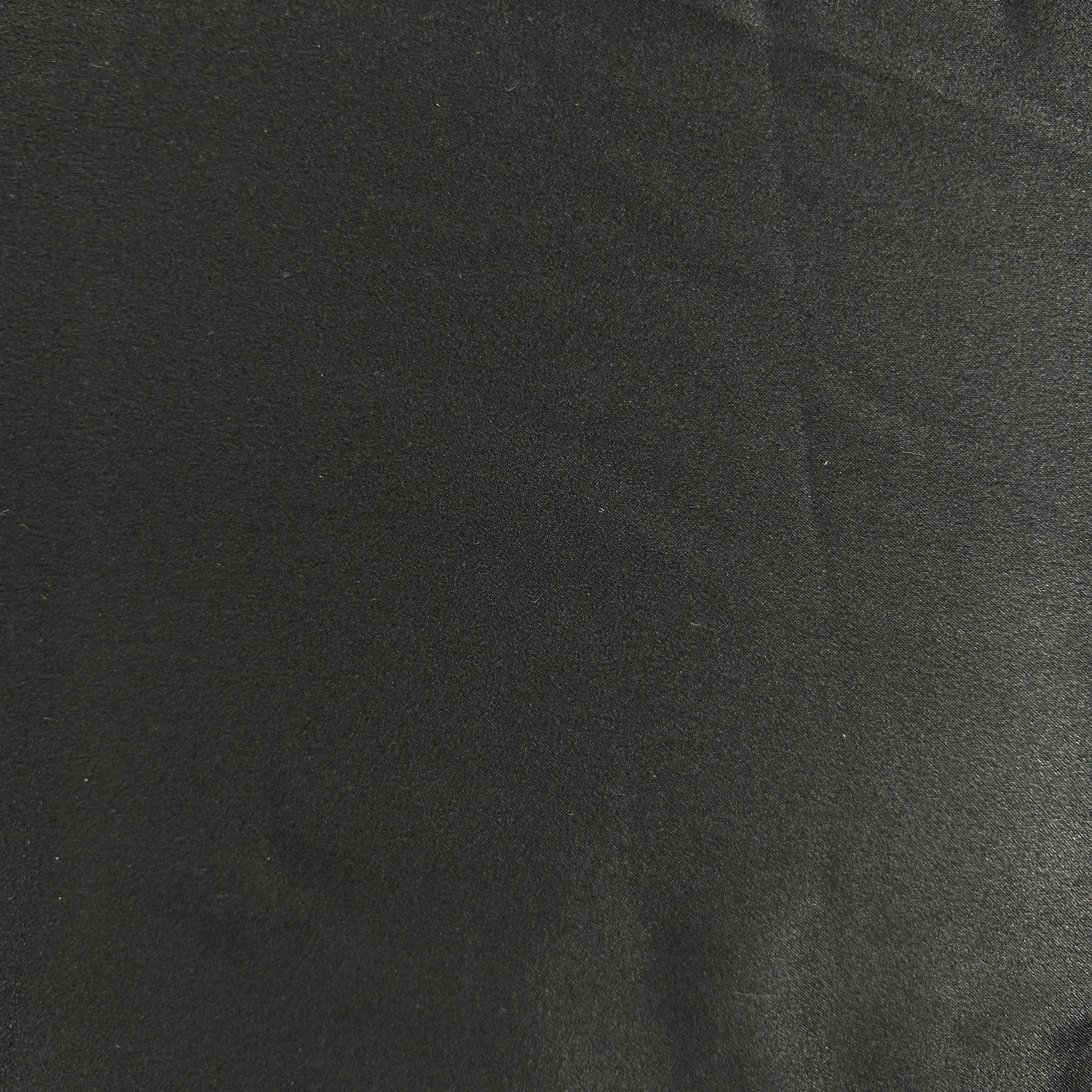 A close-up of a dark charcoal gray or black textured fabric surface with subtle folds and a matte finish.