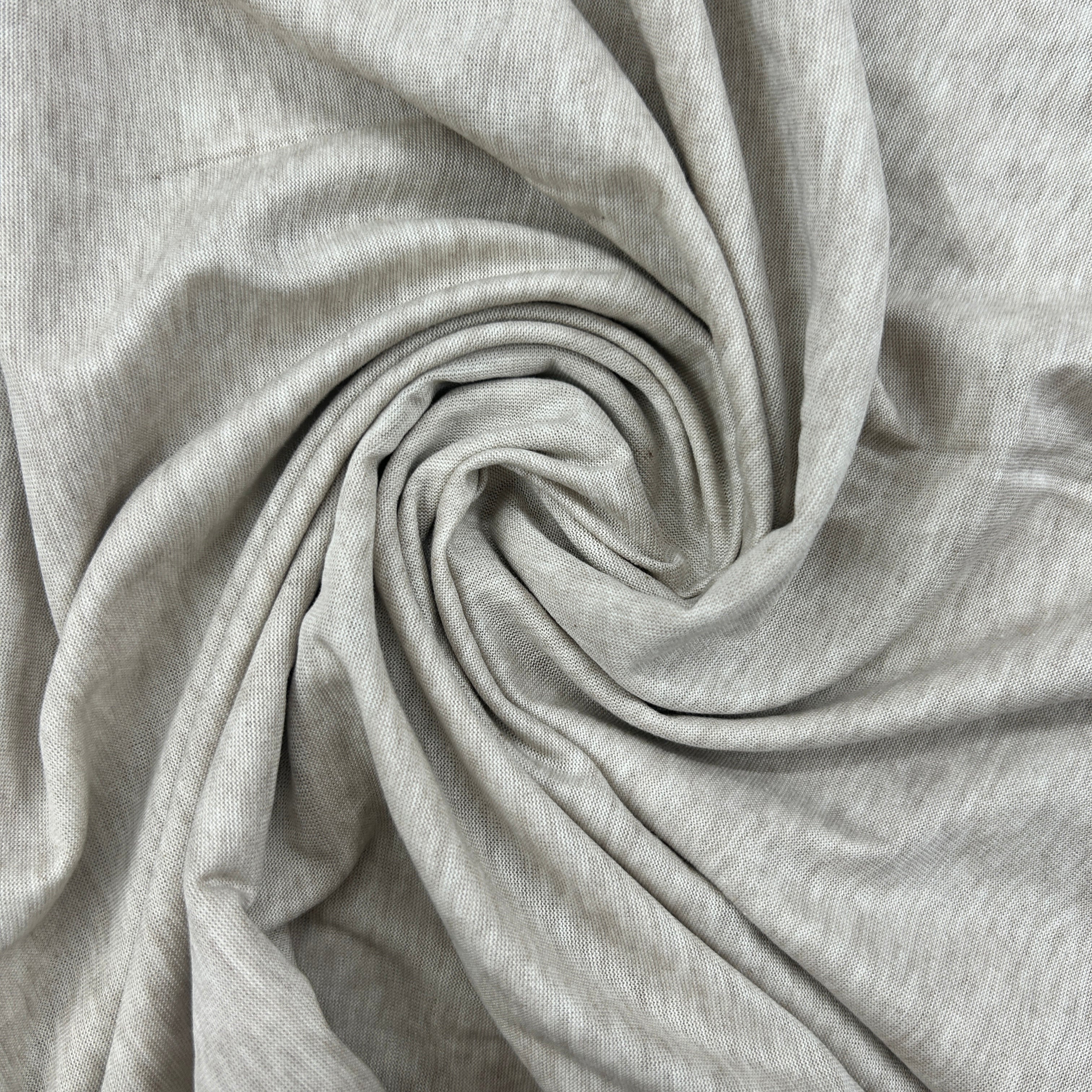 A close-up of light heather gray fabric arranged in a spiral drape, showing the material texture and soft folds.