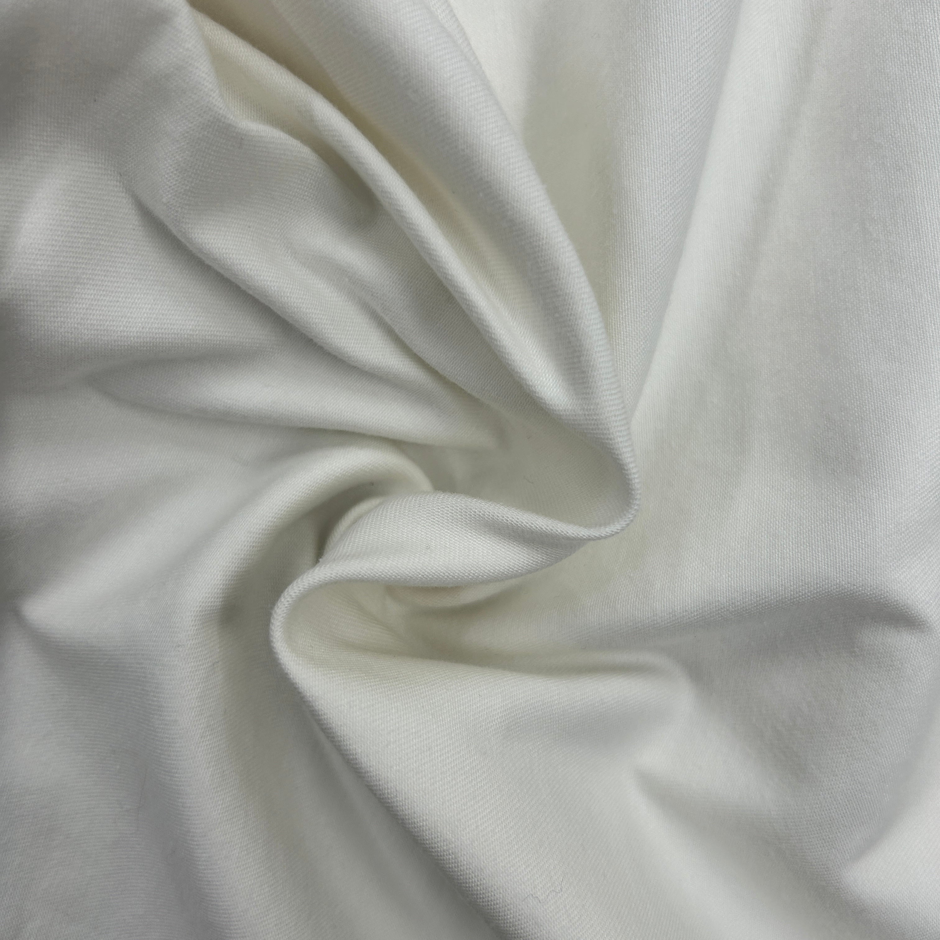 A close-up of draped off-white fabric with soft folds and a smooth texture.