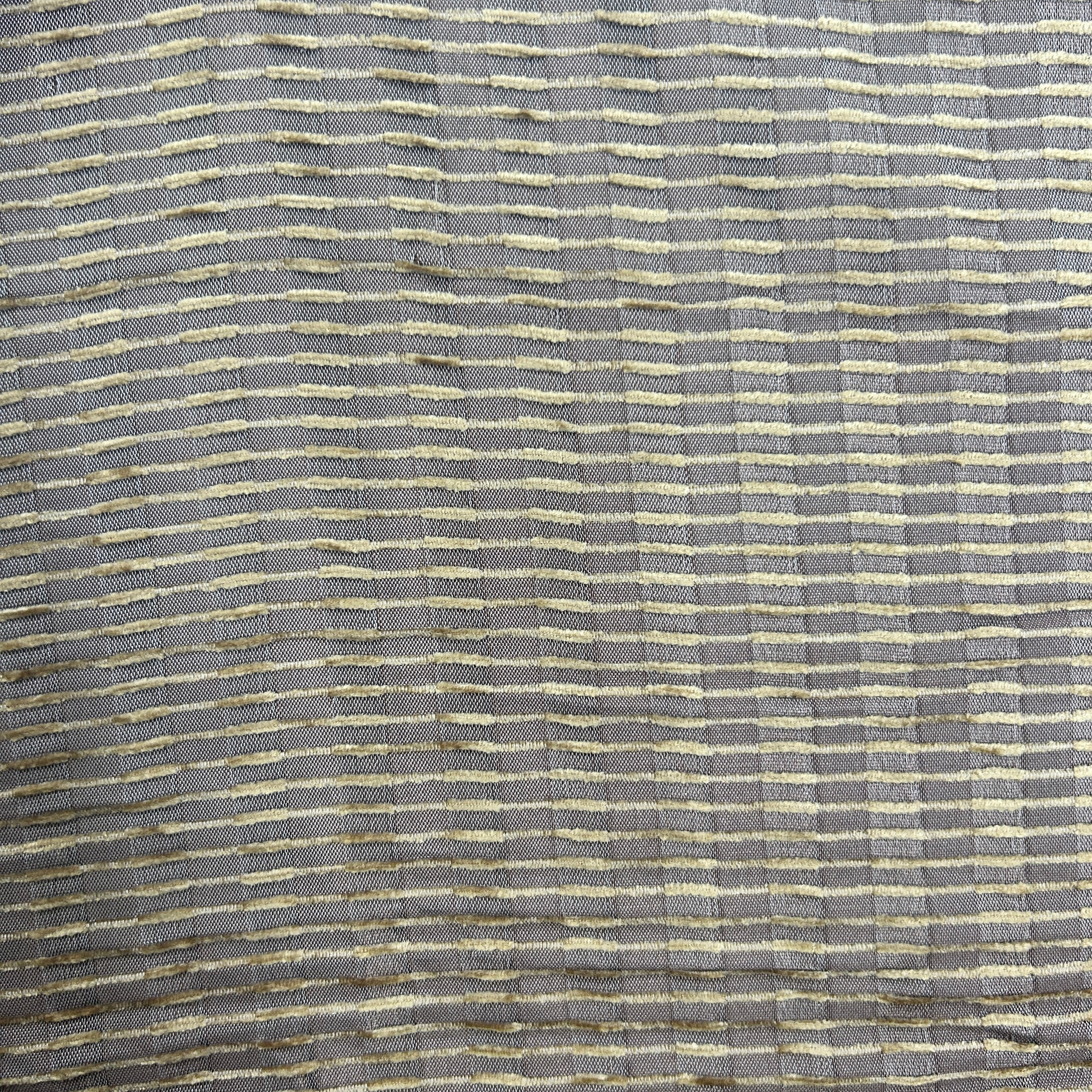A close-up of a woven fabric texture featuring a gray base with horizontal stripes of cream and gold.