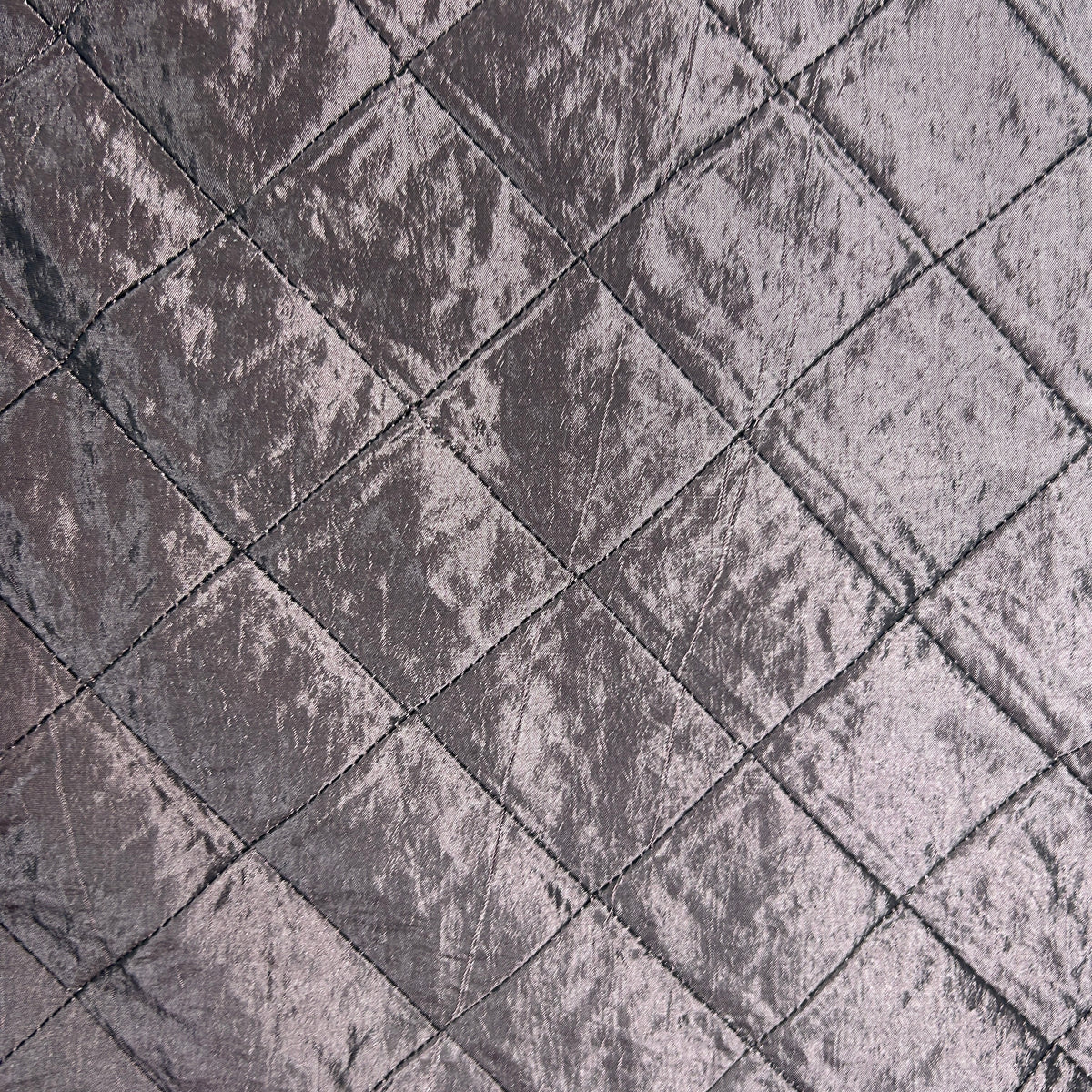 A close-up of a textured fabric with a diamond quilted pattern in a dusty mauve-gray color.