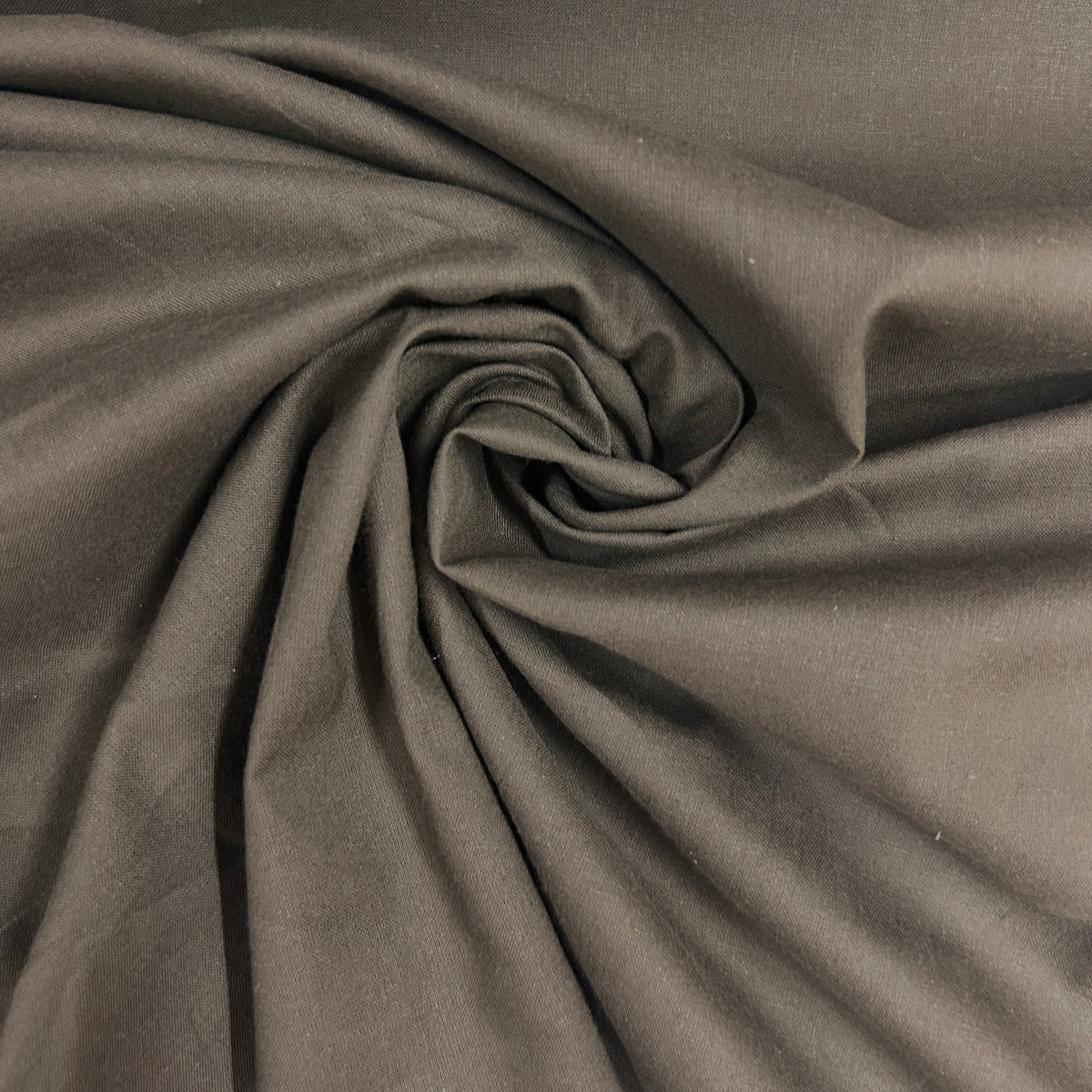 A close-up of draped dark gray fabric arranged in a spiral swirl, showing the material's texture and soft folds.