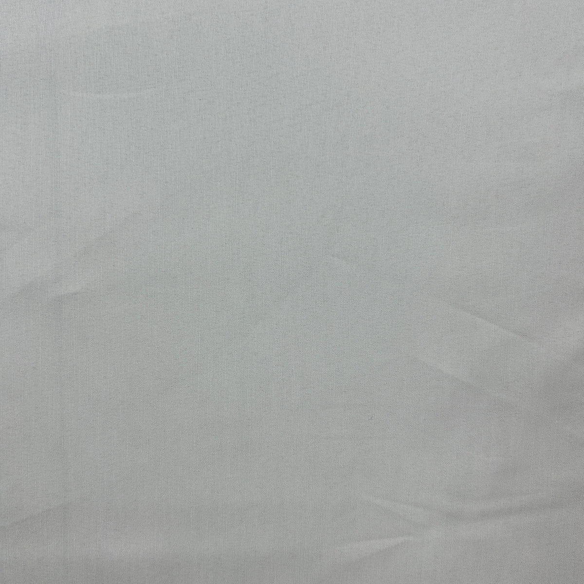 A close-up of a light gray fabric texture with subtle folds and creases.