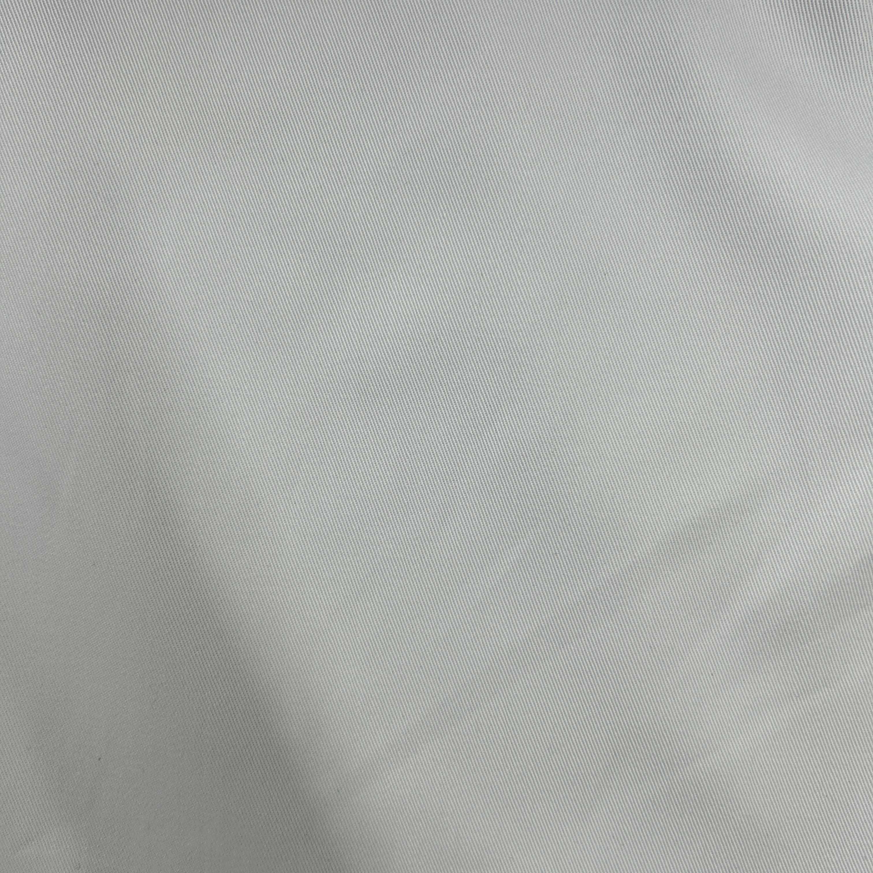 A close-up of light gray fabric with a fine woven texture and soft folds.