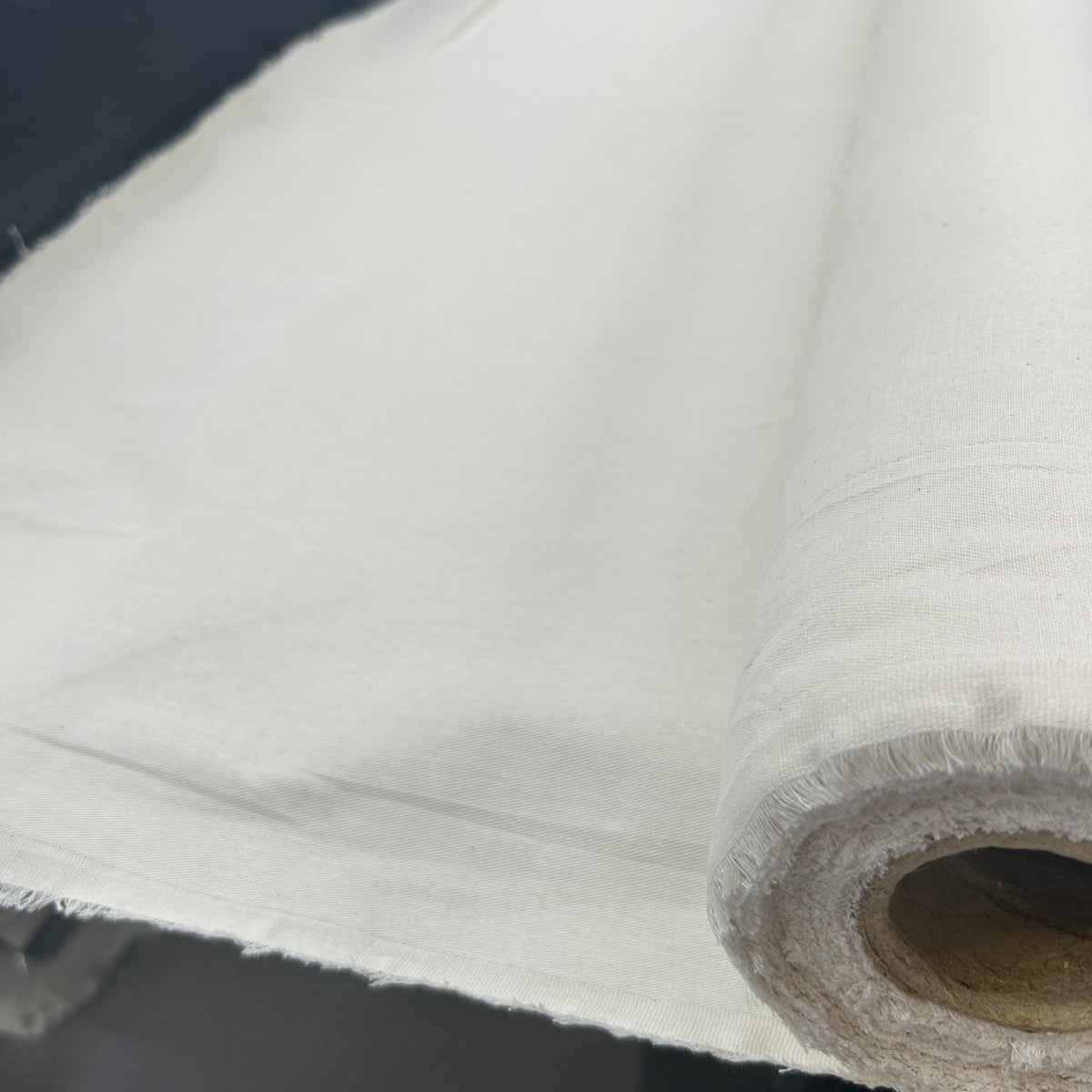 Roll of natural white heavyweight plain calico canvas fabric with a rustic texture.