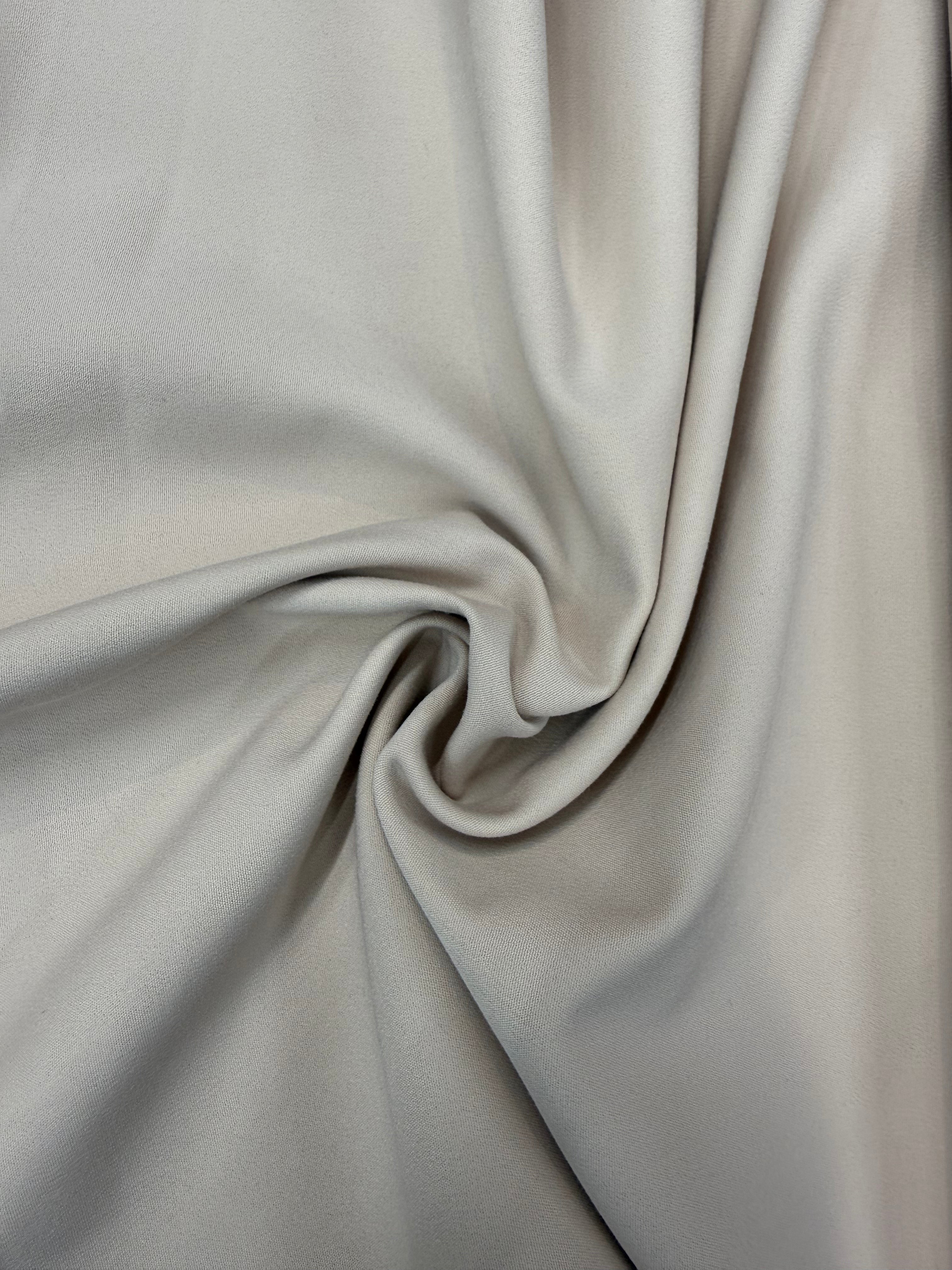 Beige cotton stretch suiting fabric with a smooth texture and soft, swirling drapes.