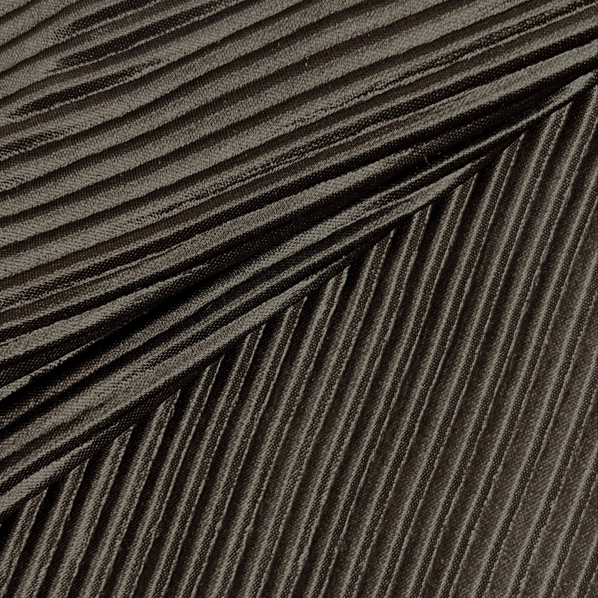 A close-up of a dark gray pleated fabric or material with tightly folded parallel ridges and a soft sheen.