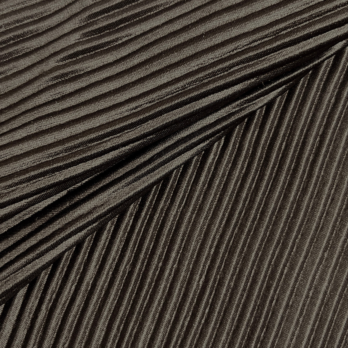 A close-up of a dark gray pleated fabric or material with tightly folded parallel ridges and a soft sheen.