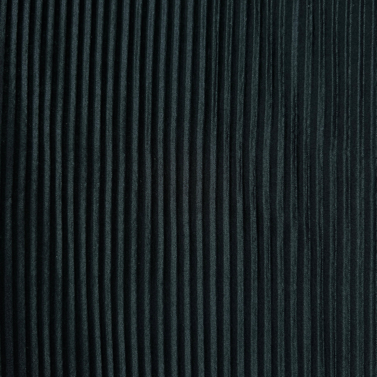 A close-up of a dark charcoal gray pleated fabric texture with vertical pleats.