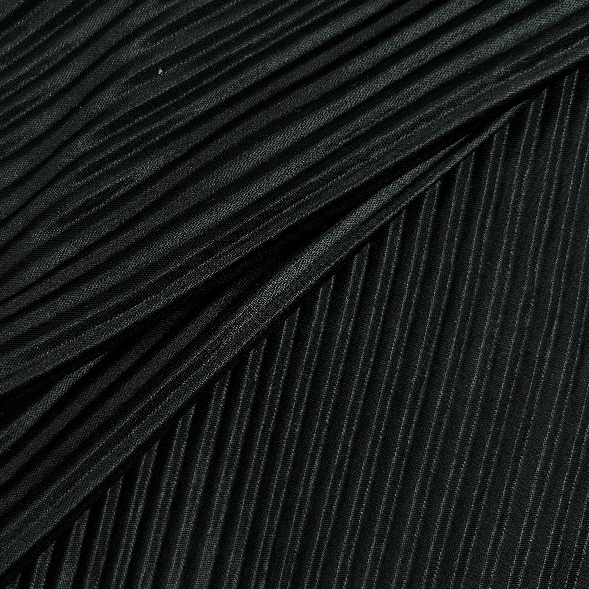 Close-up of a black pleated fabric with tightly folded vertical pleats and a soft sheen.