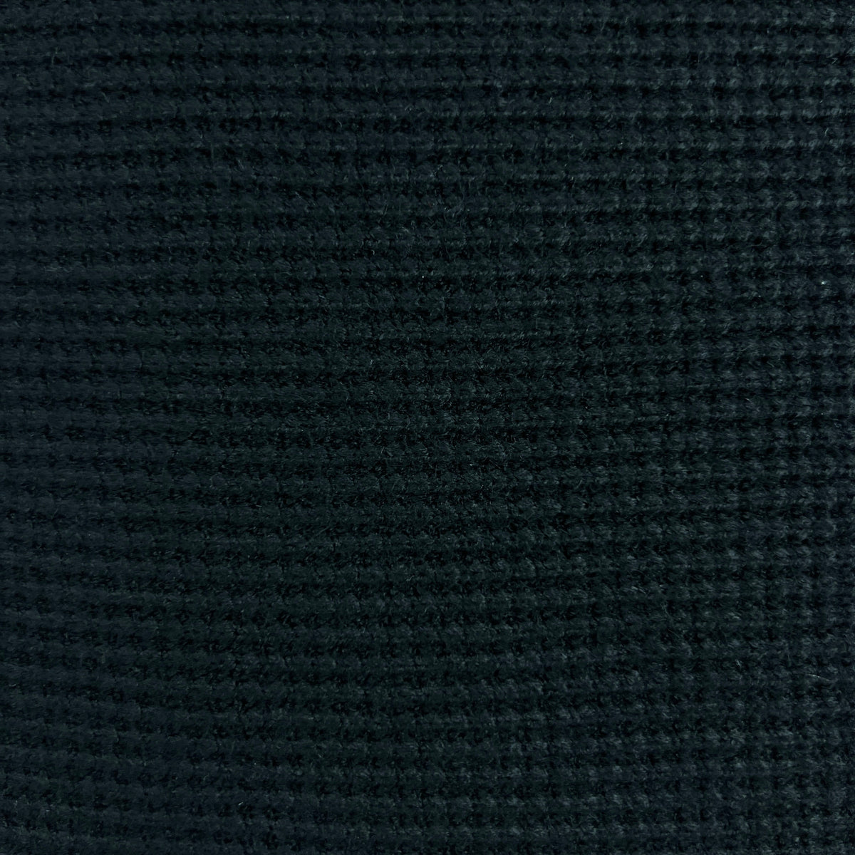 A close-up of a dark navy blue textured fabric with a waffle or grid-like woven pattern.