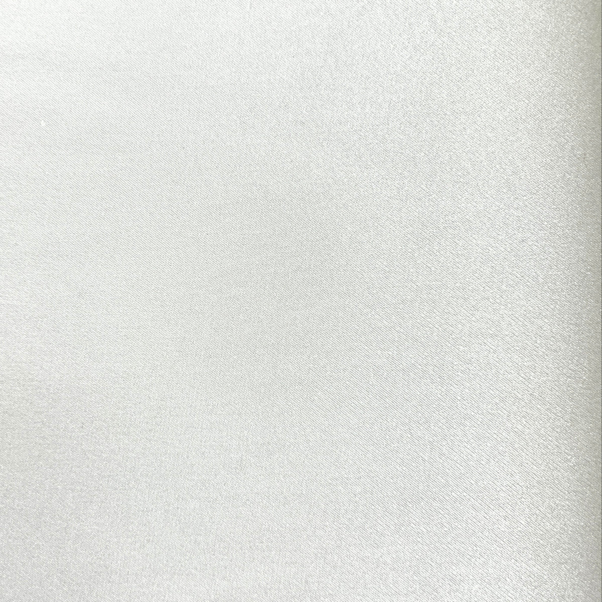 A close-up of a light silver or white textured material surface with subtle sheen and fine grain.
