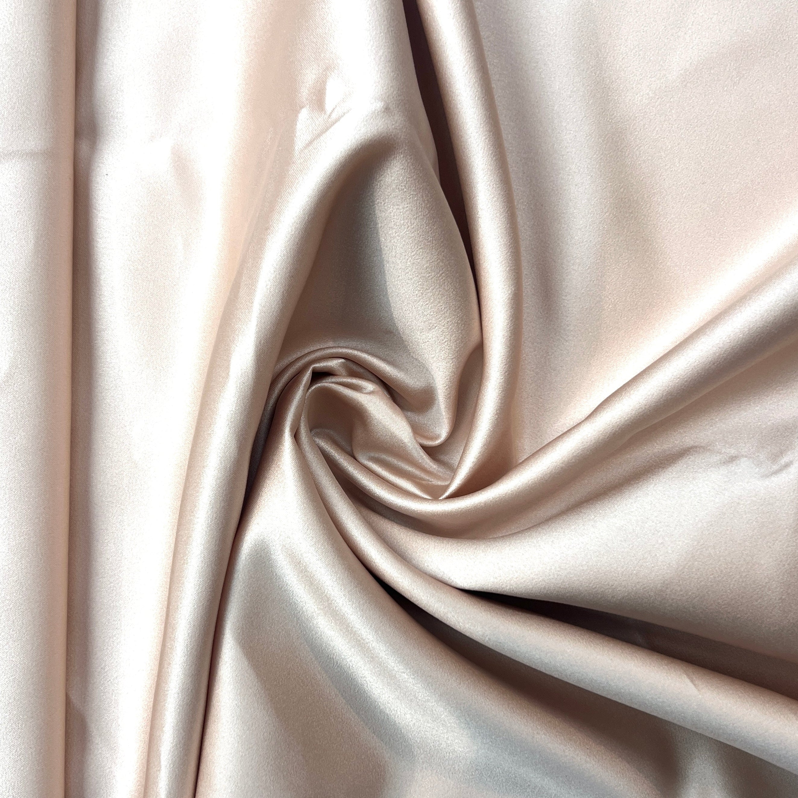 Close-up of beige satin fabric with folds