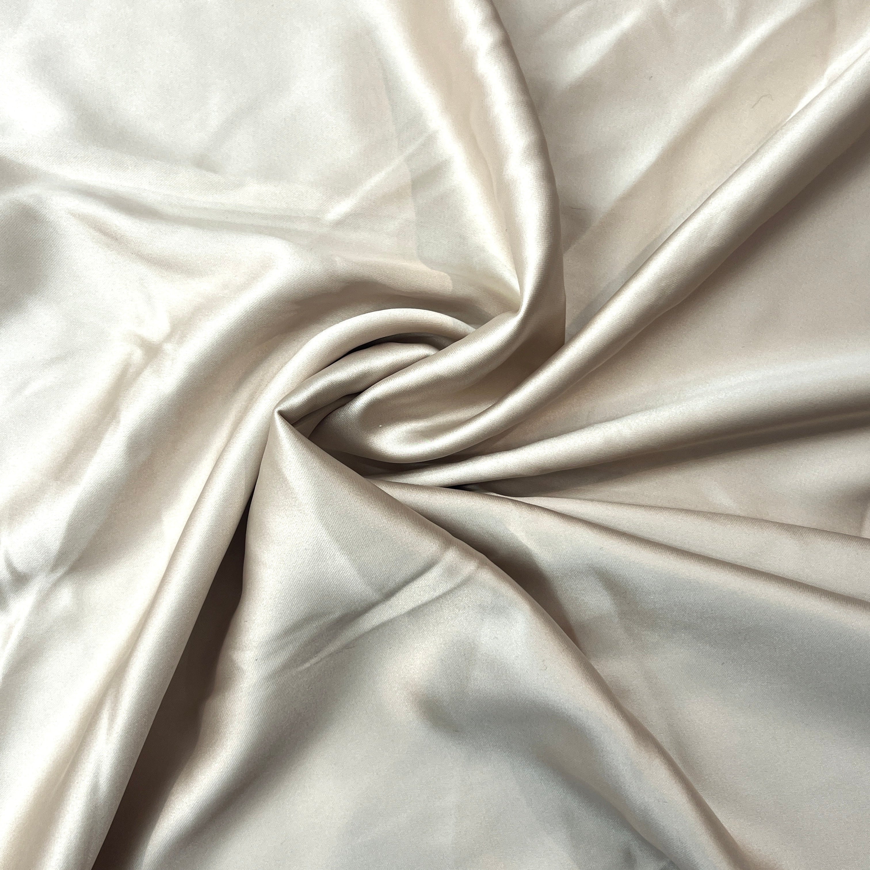 Close-up of beige satin fabric with folds