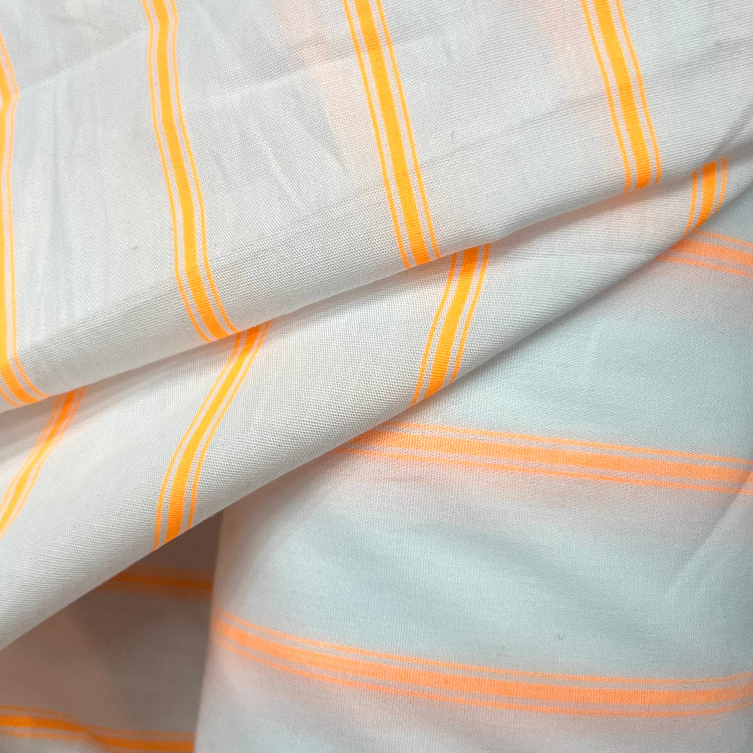 Close-up of white fabric with orange stripes on a gray background