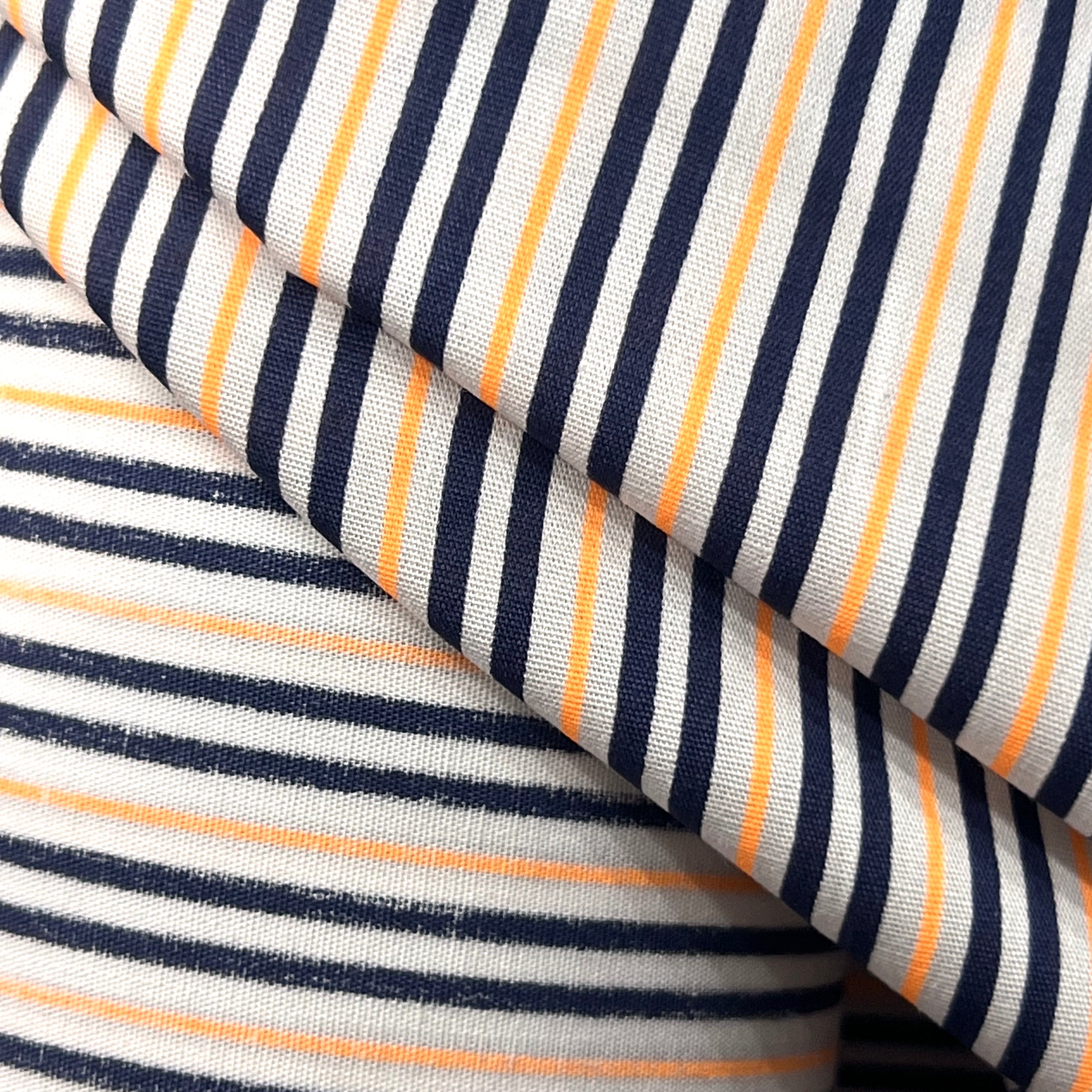 Close-up of striped fabric with navy, white, and orange lines.